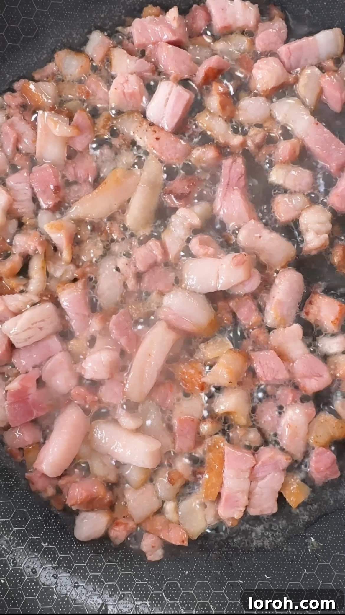 Pancetta cubes frying in a non-stick pan until crispy and golden brown, highlighting the texture.