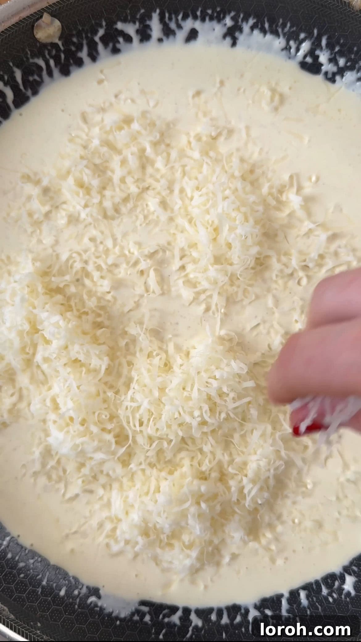 Double cream, Dijon mustard, and grated Gruyere cheese being gently heated in a saucepan to create a smooth, velvety sauce.