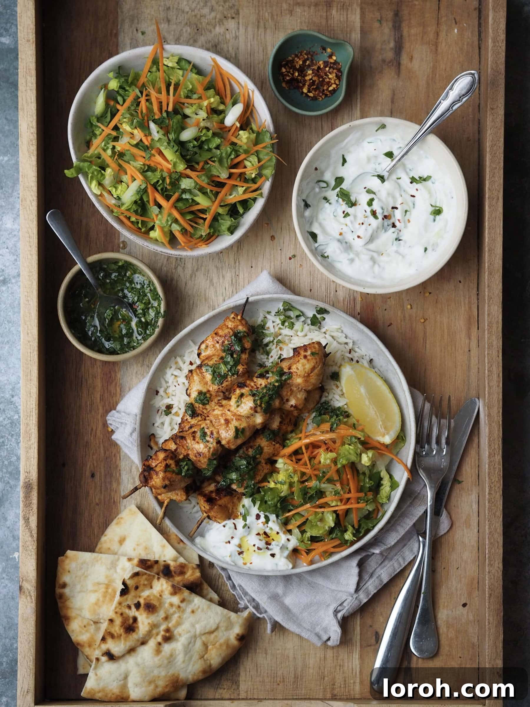 Plated baked chicken skewers with all the delicious sides arranged beautifully.