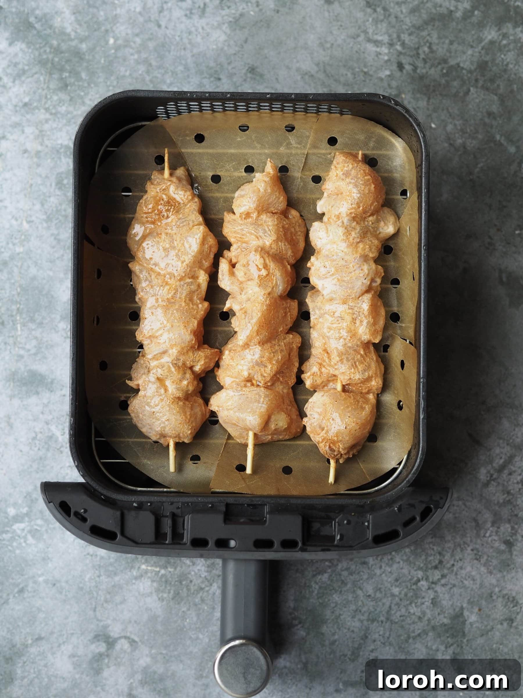 Chicken skewers neatly arranged on a baking tray, ready for the oven.