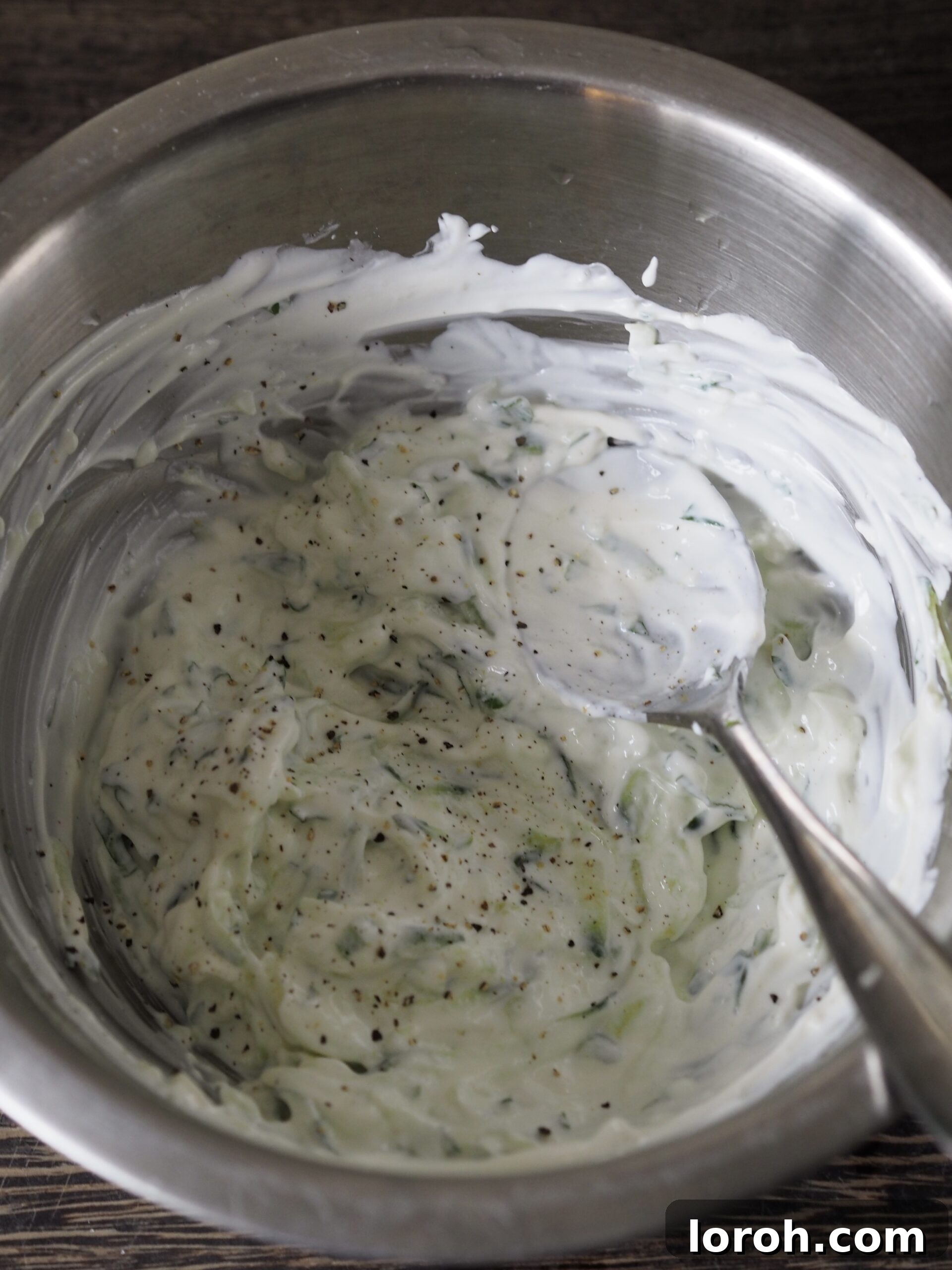 The raita mixture being stirred until smooth and well combined.