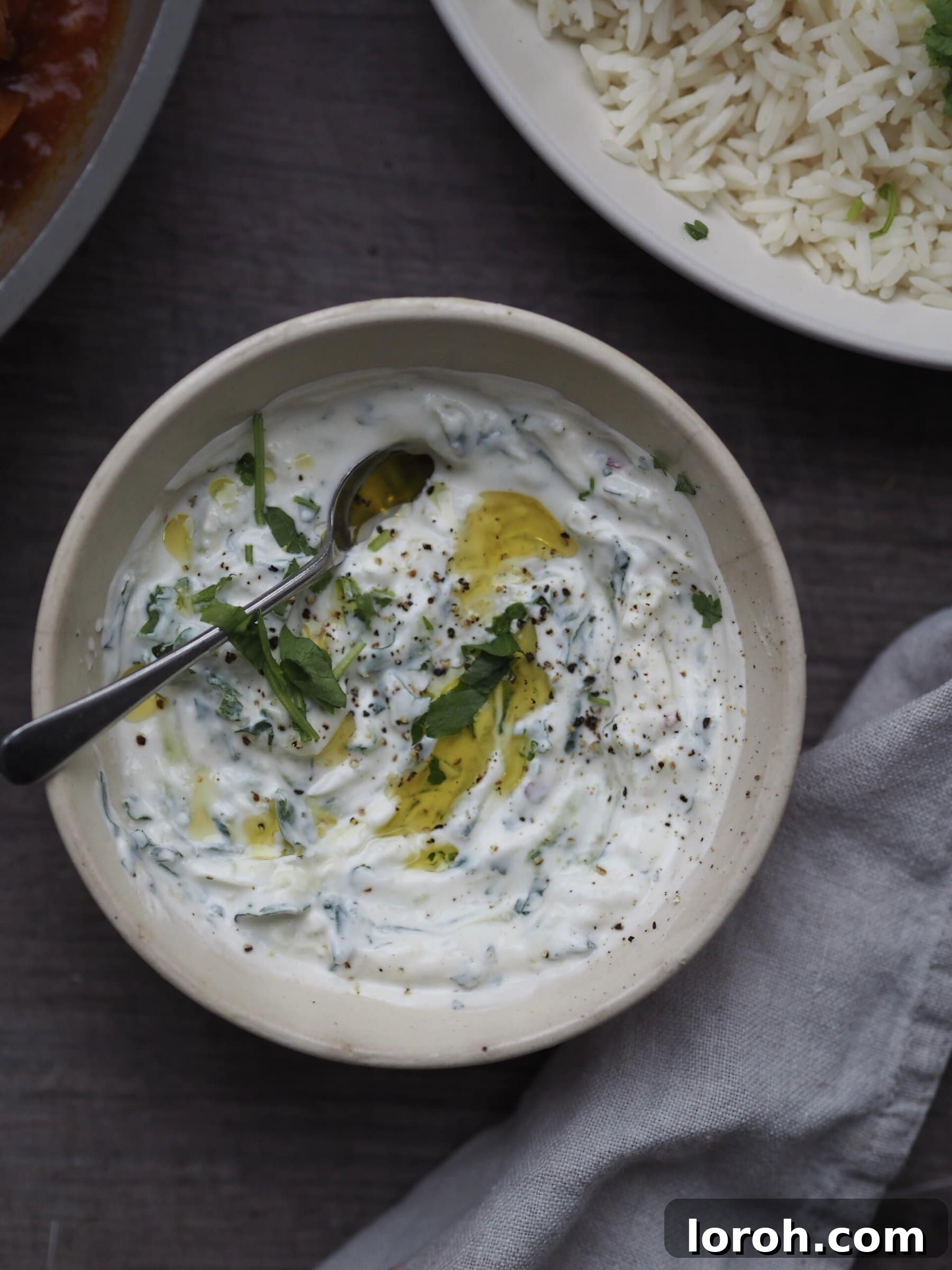 Grated cucumber and other ingredients being mixed in a bowl to make tzatziki.
