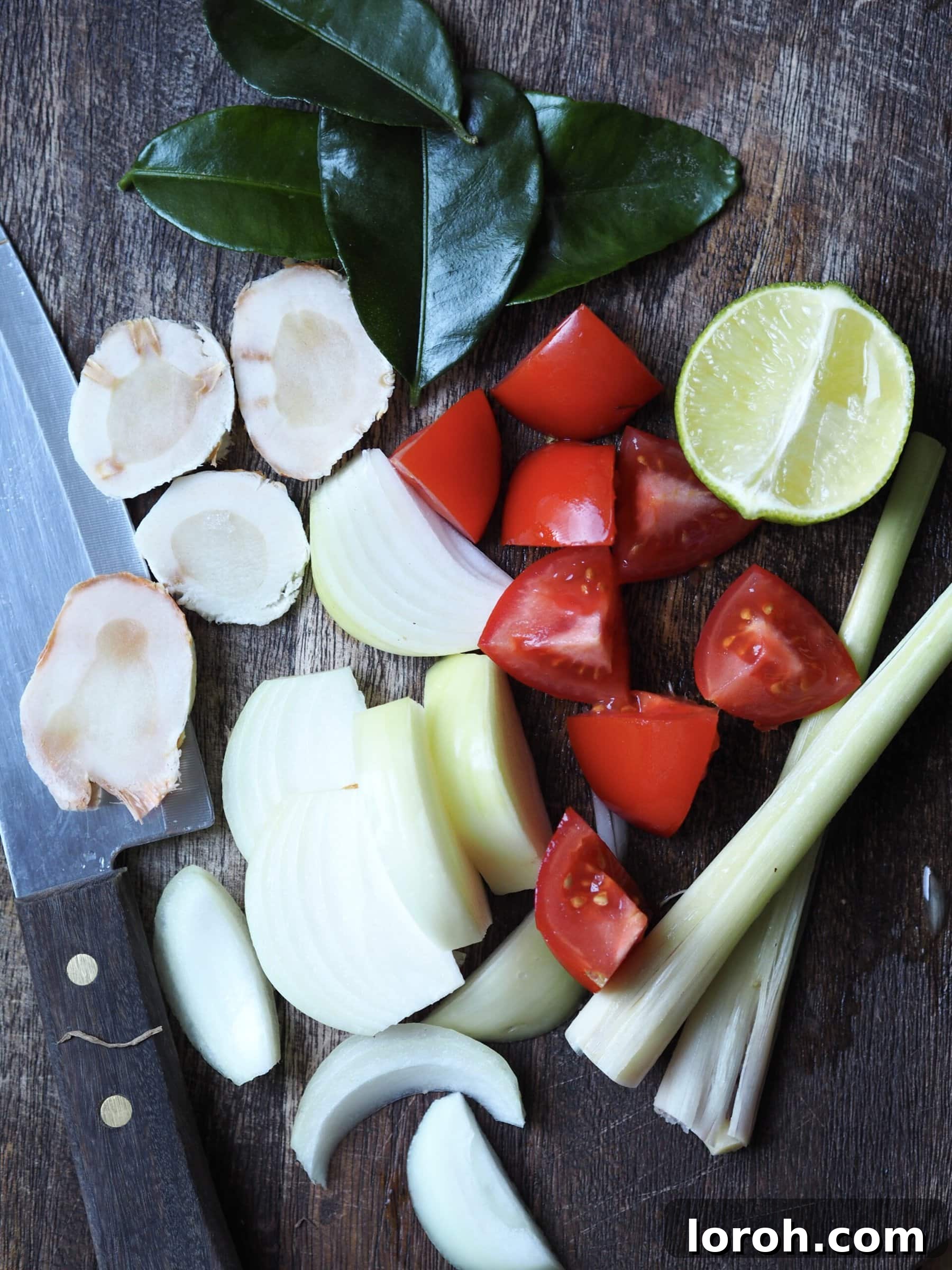 Vibrant Chicken and Prawn Tom Yum Soup 5 Fresh ingredients for tom yum soup laid out on a wooden chopping board, including chicken, prawns, lemongrass, and lime.