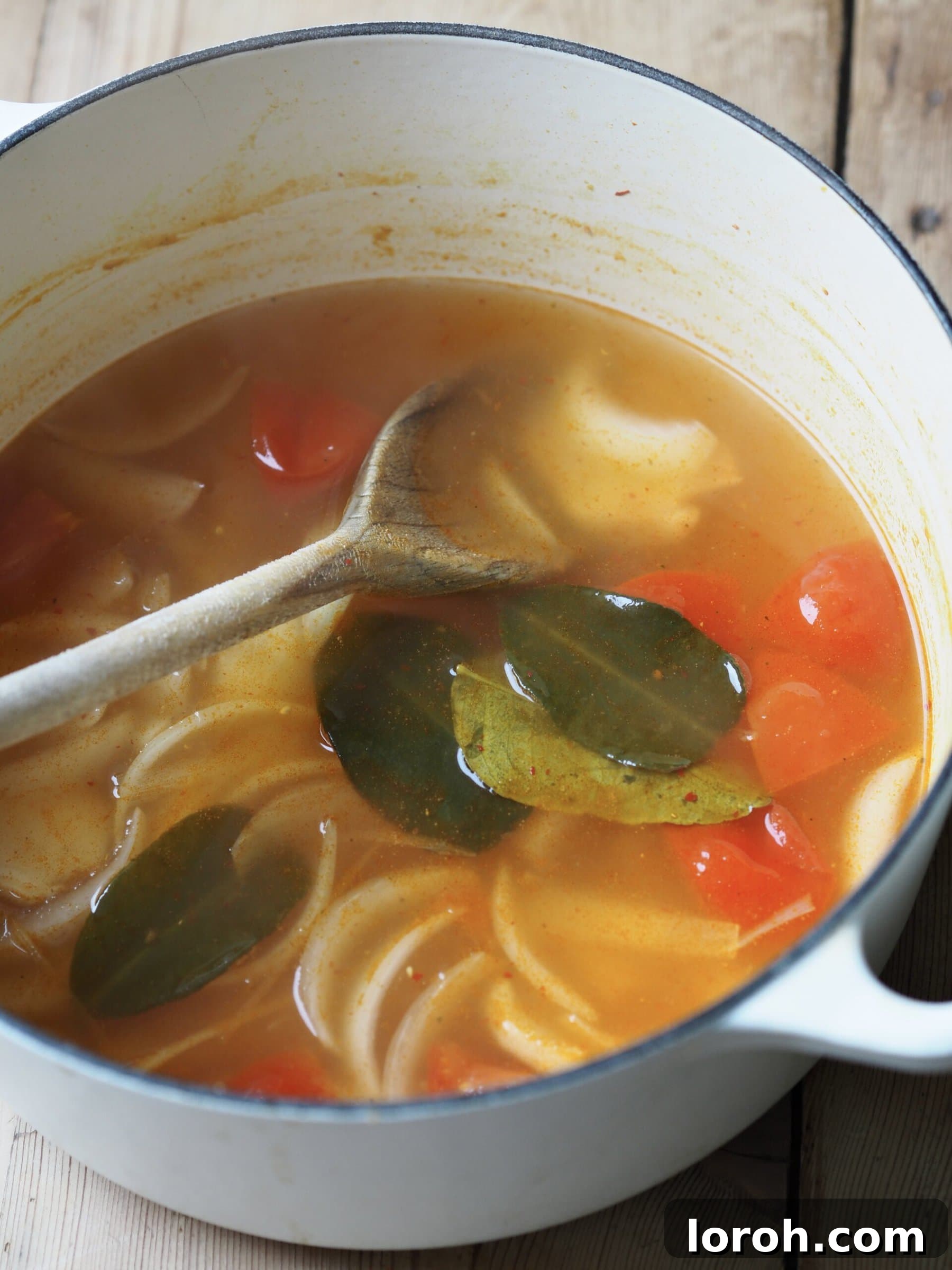Vibrant Chicken and Prawn Tom Yum Soup 7 Sliced chicken strips and chopped tomatoes being added to the simmering tom yum soup broth in a pan.