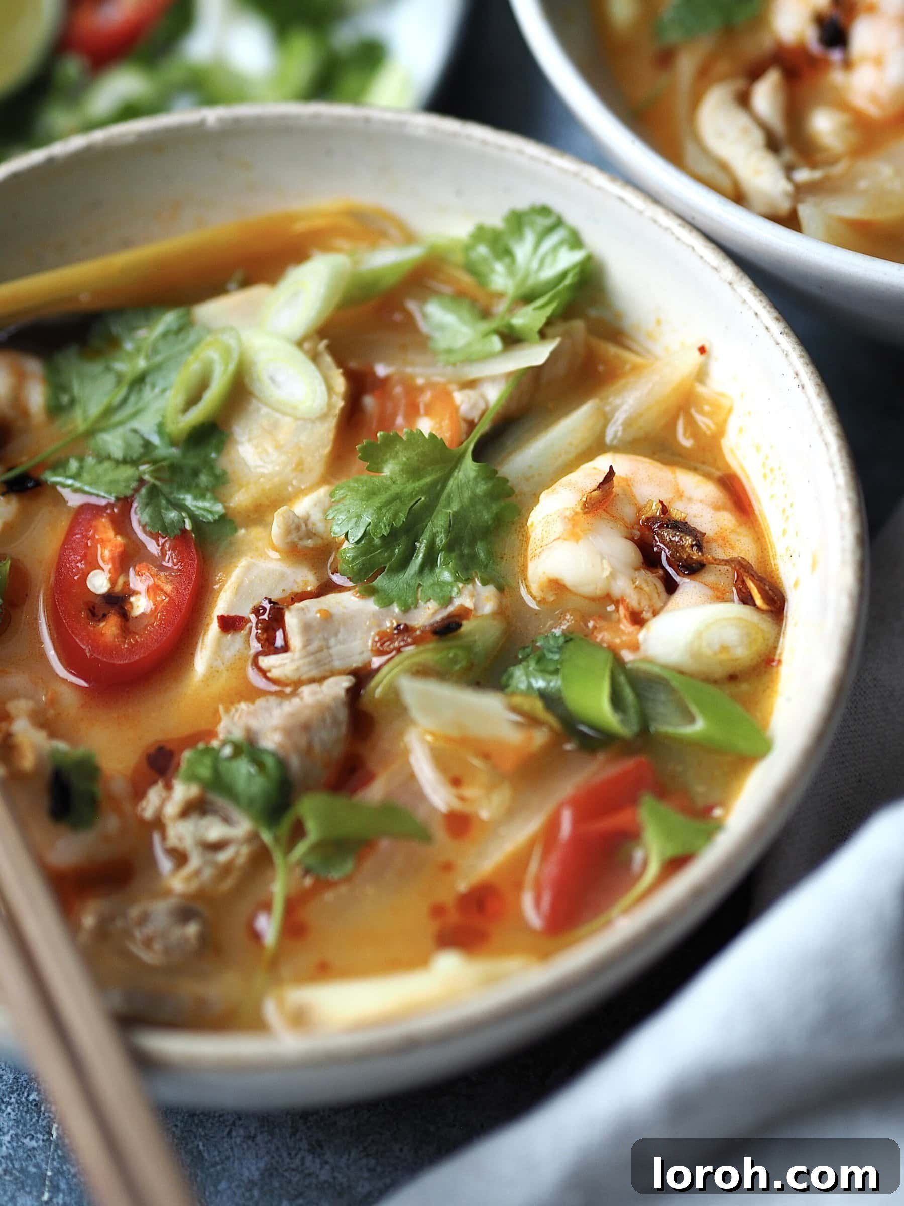 Vibrant Chicken and Prawn Tom Yum Soup 9 A beautifully presented bowl of chicken and prawn tom yum soup, topped with fresh herbs and chili, ready to be enjoyed.