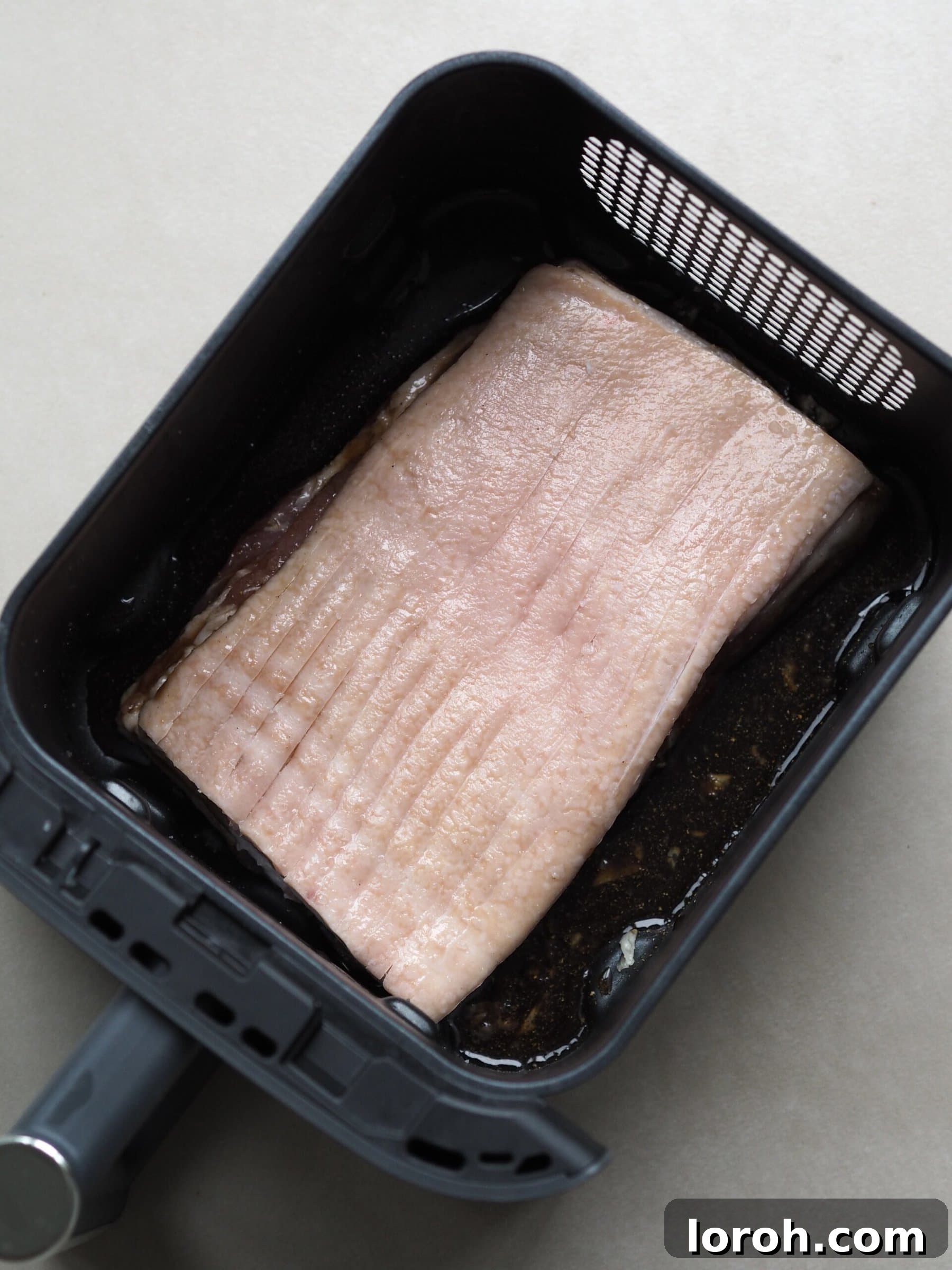 Pork belly prepared for air frying, with scored skin.
