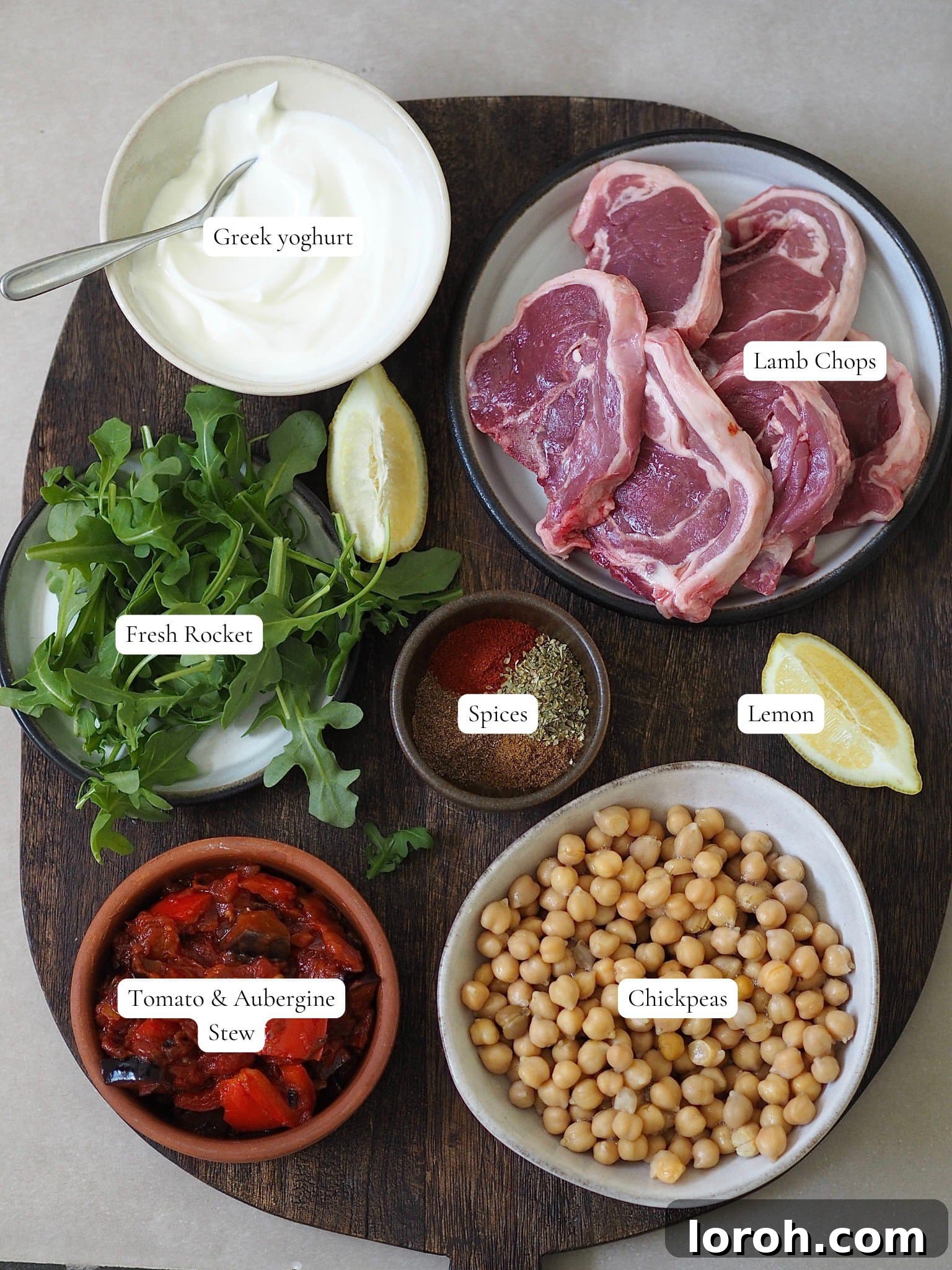 A selection of ingredients for air fryer lamb chops including spices, Greek yogurt, chickpeas, and fresh vegetables.