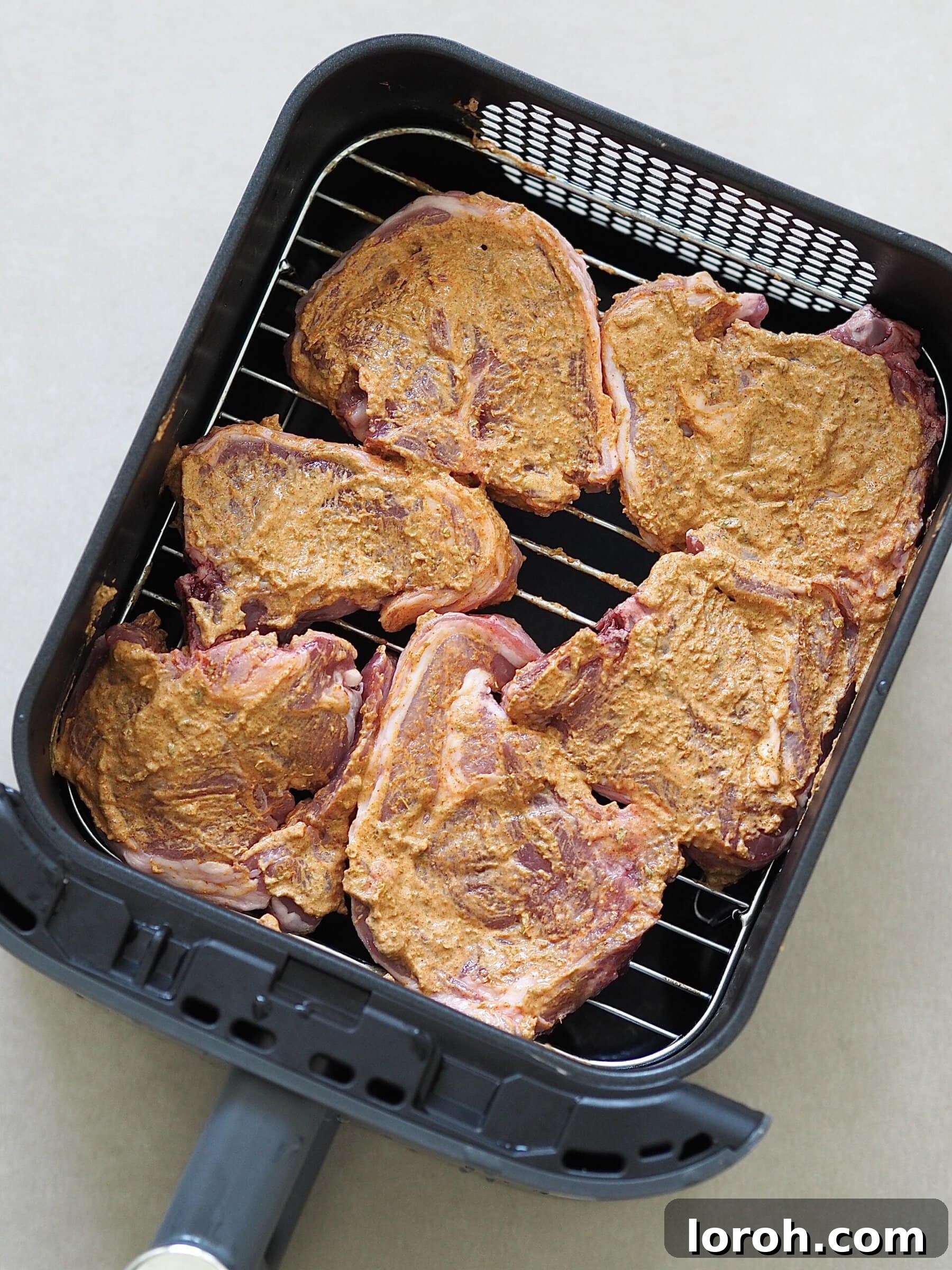 Lamb chops coated in a yogurt and spice marinade in a dish.