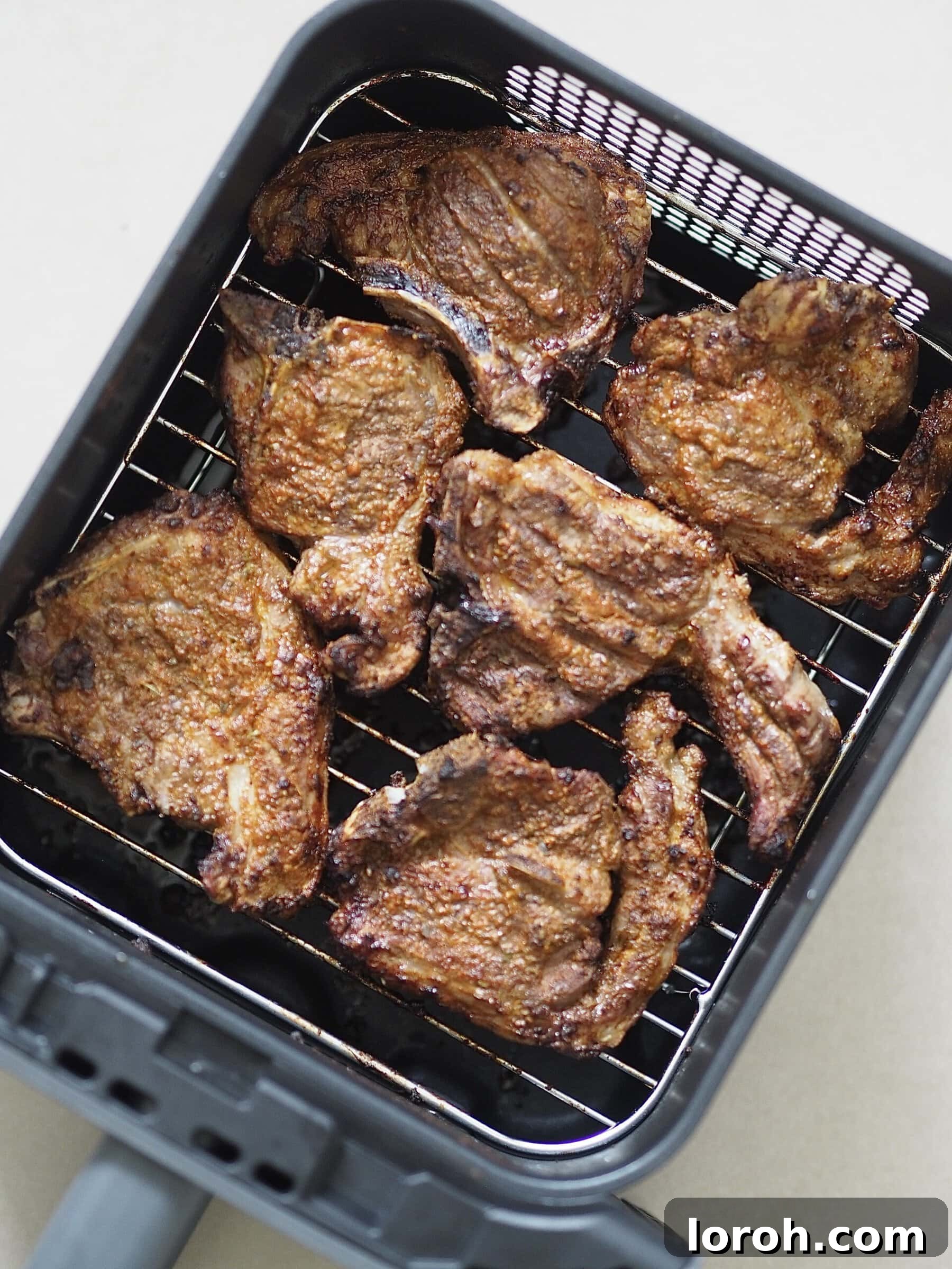 Marinated lamb chops cooking in an air fryer basket.