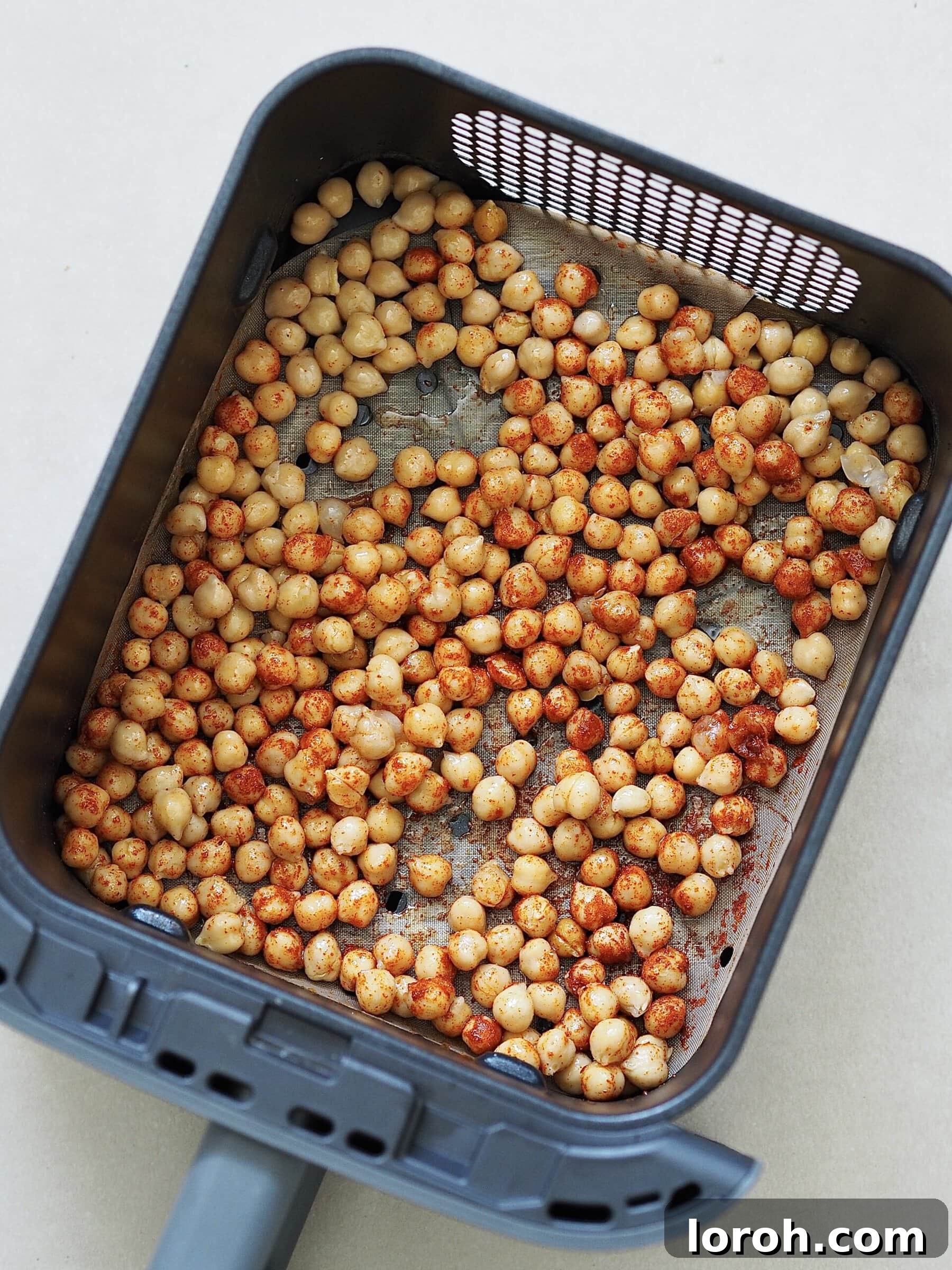 Drained chickpeas seasoned with olive oil and paprika, ready for air frying.