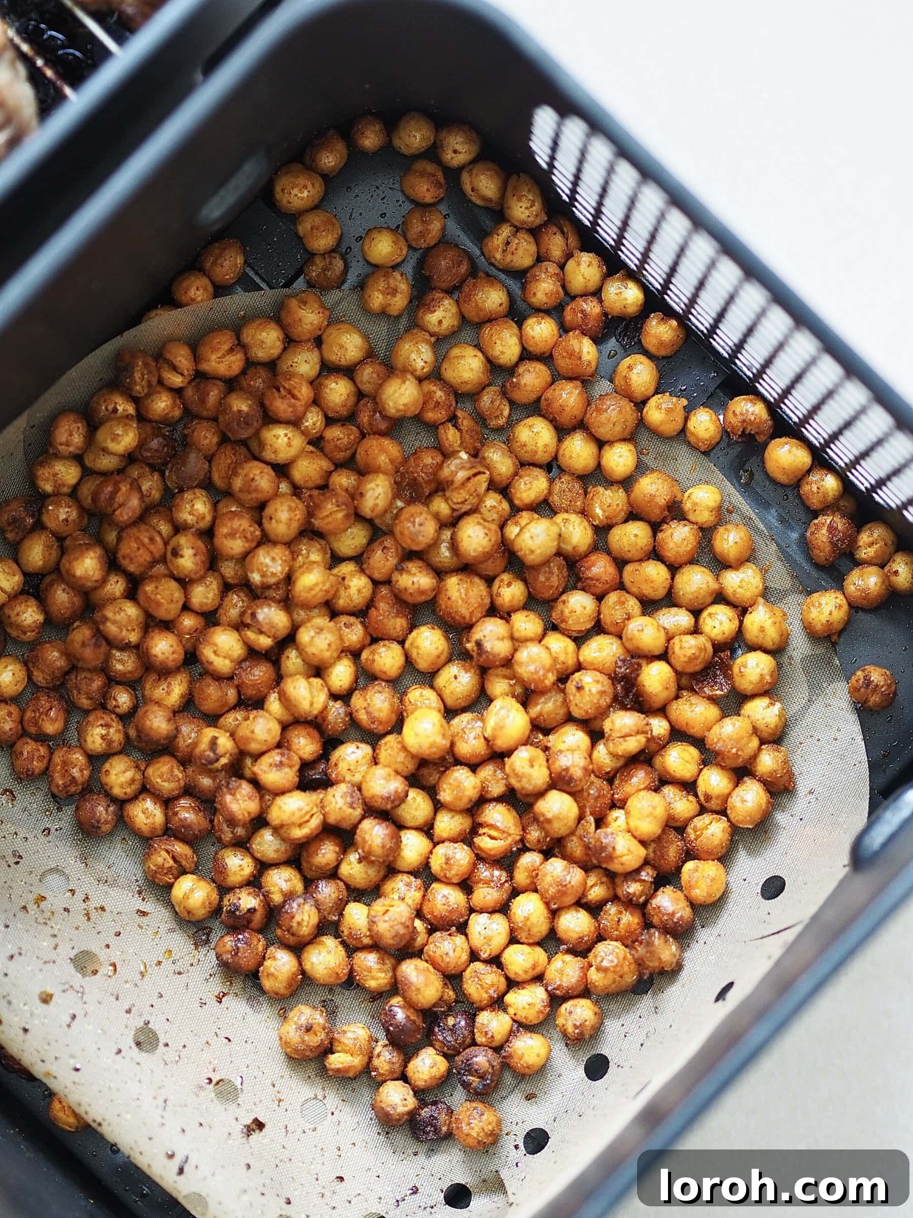 Crispy spiced chickpeas cooking in an air fryer basket.