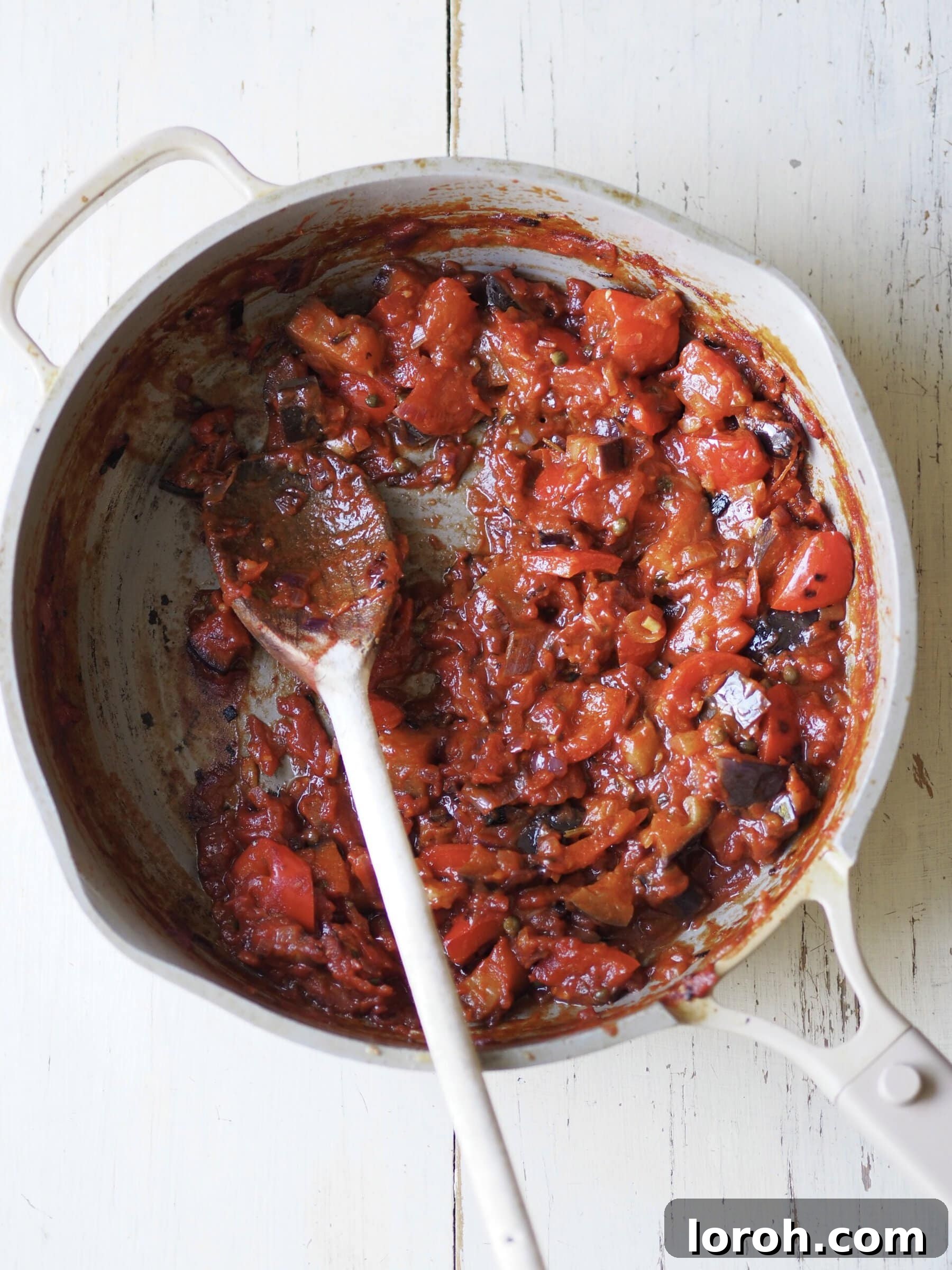 A vibrant tomato and aubergine stew simmering in a frying pan.