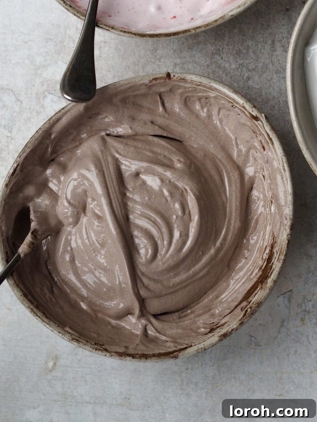 Folding cocoa powder into the whipped marshmallow mixture.
