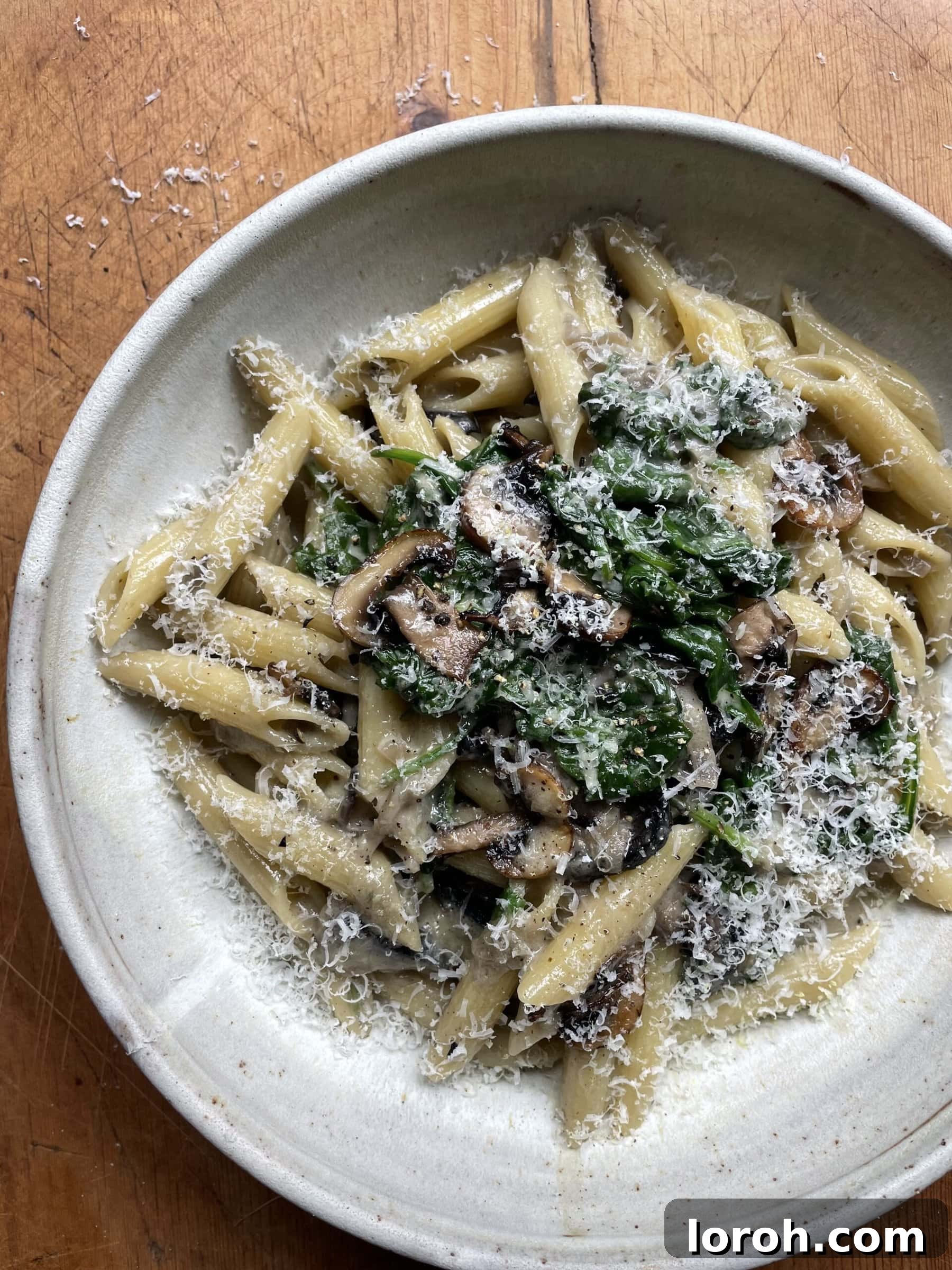 A tantalizing view of creamy mushroom and spinach pasta, ready to be served, in a stylish grey bowl.