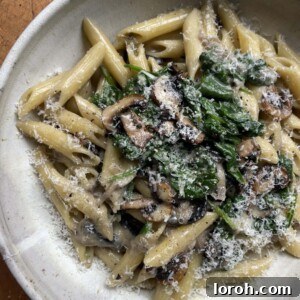 Creamy mushroom and spinach pasta in a grey bowl, ready to be served.