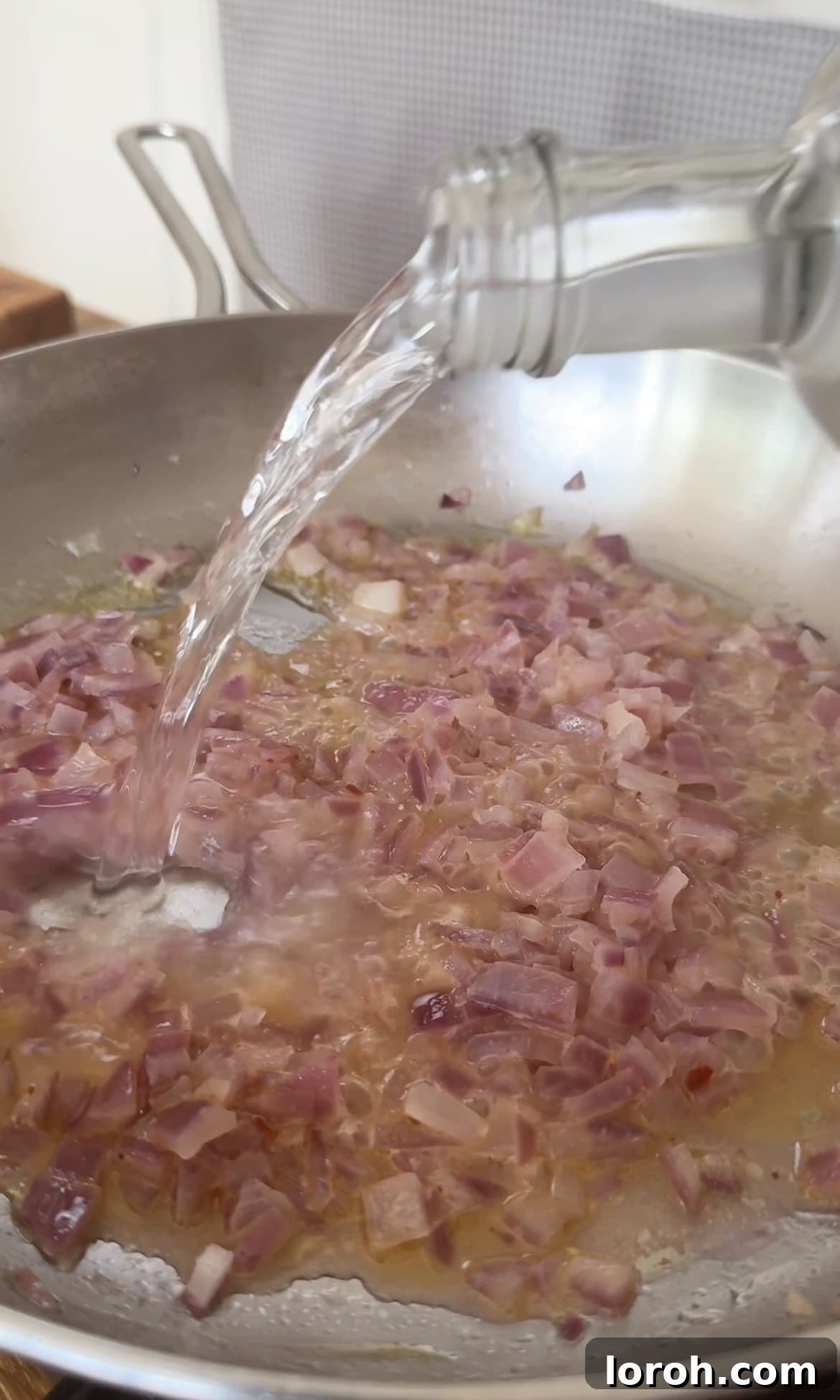 Velvet Vodka Chicken Pasta 5 Adding vodka to sautéed onions and garlic in a pan for vodka pasta sauce.
