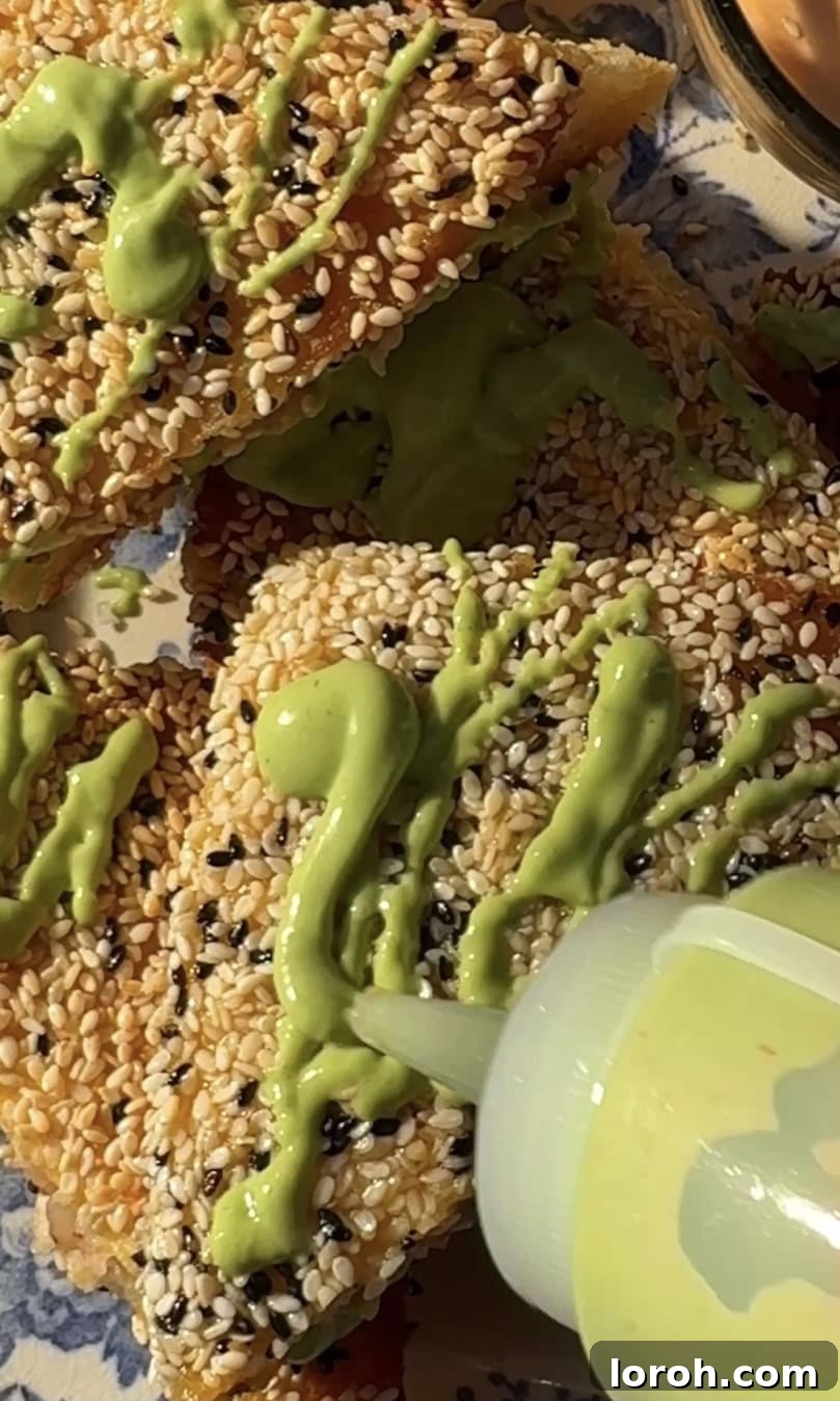 Golden Sesame Shrimp Crisps 11 Drizzling vibrant green sauce over the freshly fried sesame prawn toasts on a serving plate.