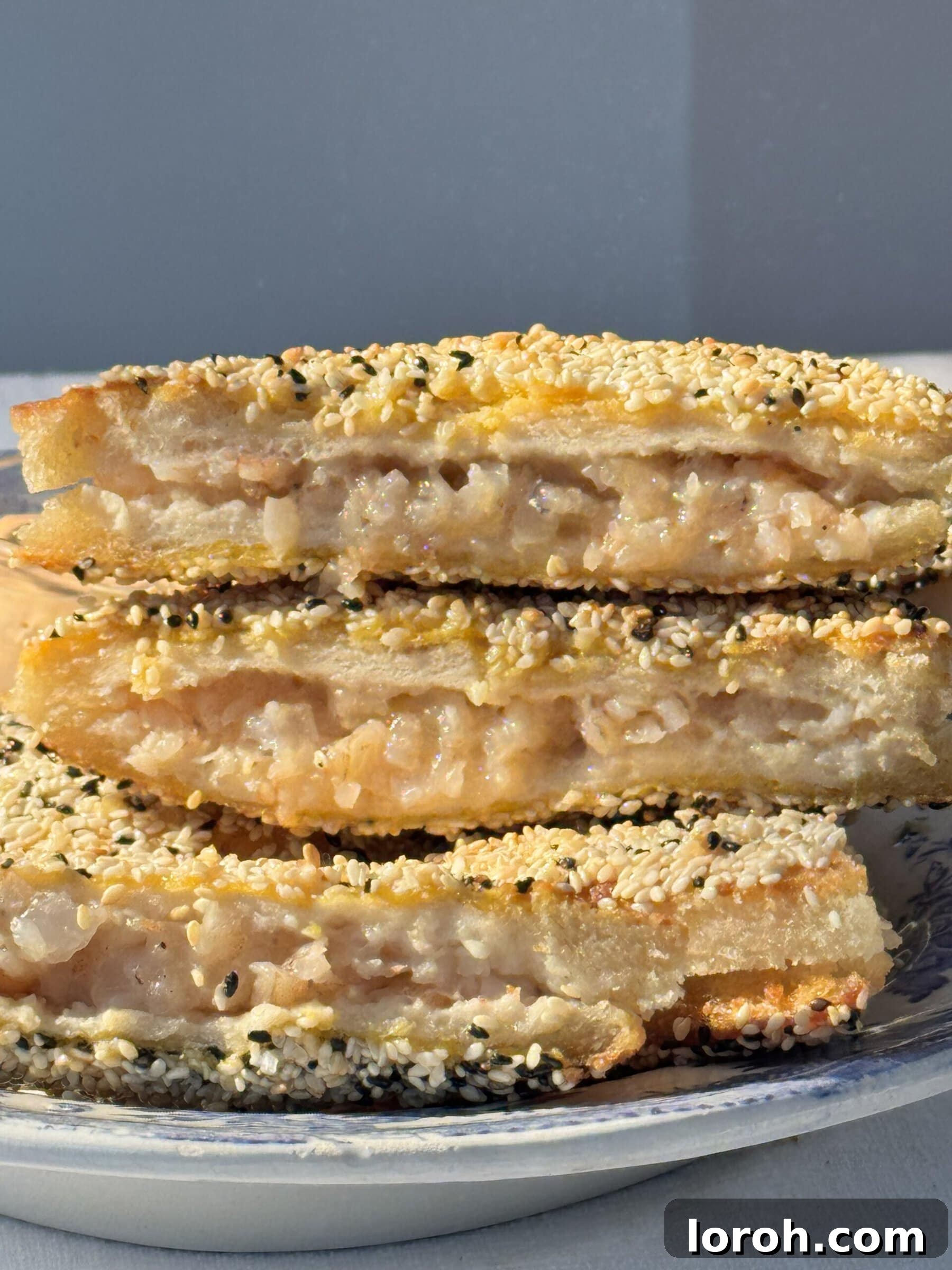 Golden Sesame Shrimp Crisps 3 Neatly stacked crispy sesame prawn toasts, golden brown and garnished, showcasing their inviting texture.