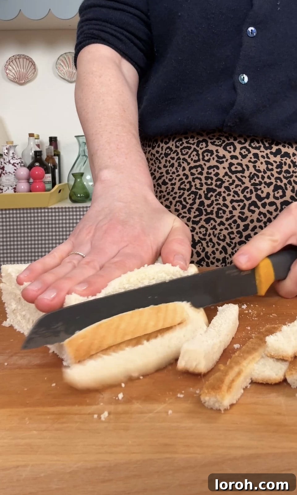 Golden Sesame Shrimp Crisps 7 Slicing the crusts off multiple pieces of white bread simultaneously for efficiency.