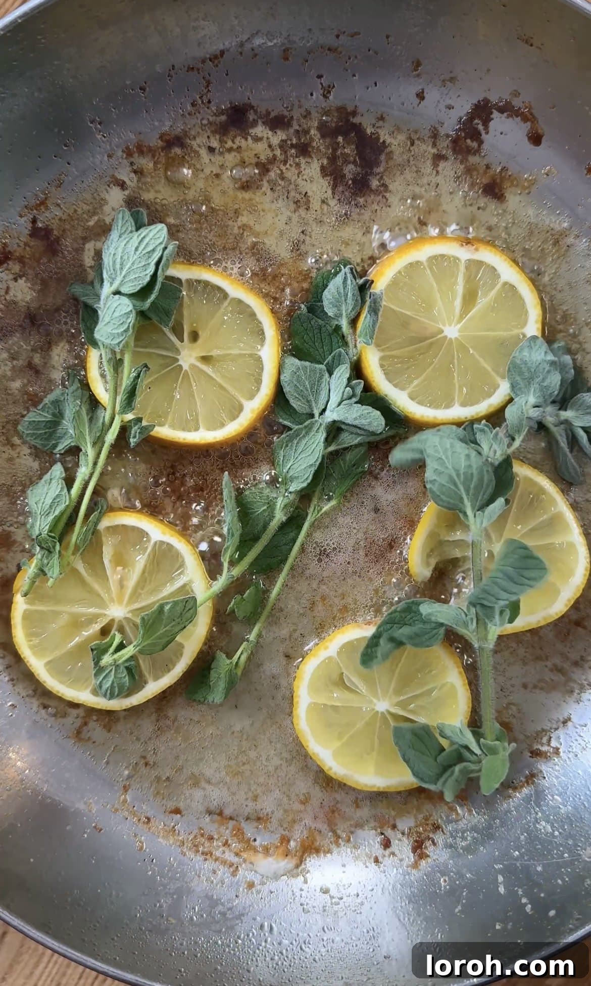 Zesty Lemon Chicken Orzo 6 frying lemon slices and fresh oregano in butter, releasing aromatic oils.