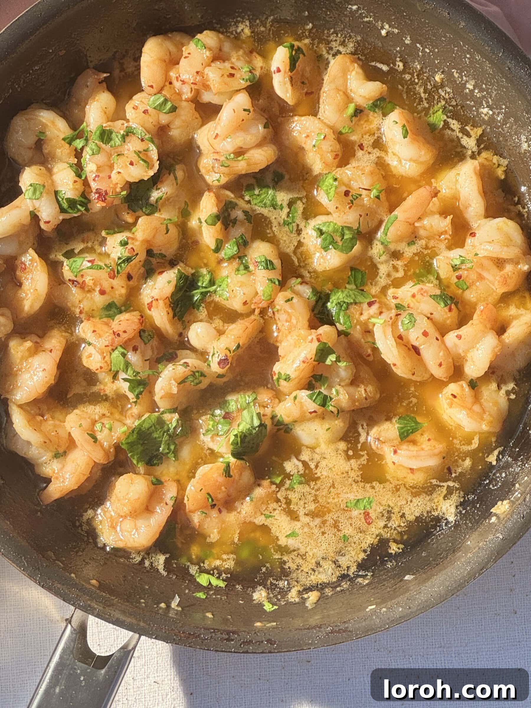 Sizzling Garlic Butter Prawns 2 buttered garlic prawns in frying pan with parsley.