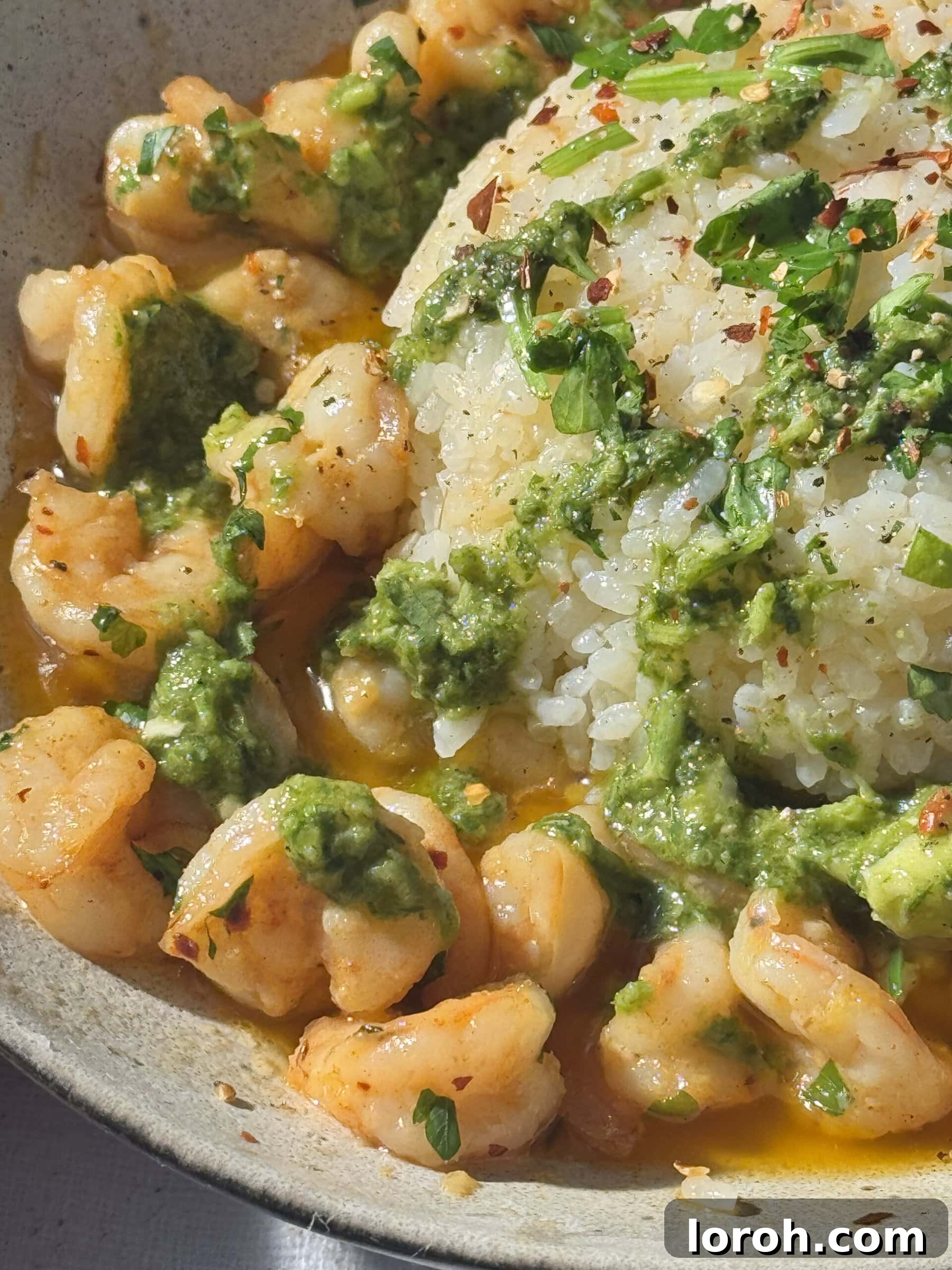 Sizzling Garlic Butter Prawns 3 buttered garlic prawns with fluffy white rice and parsley in a grey bowl.