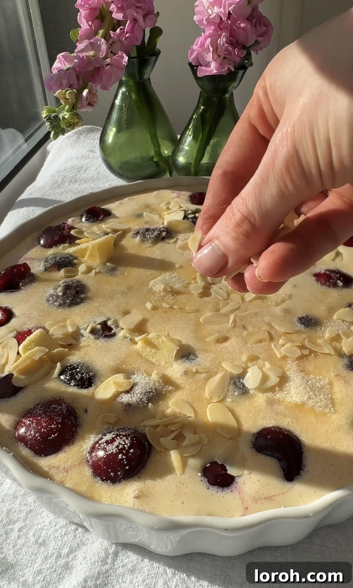 Classic French Cherry Clafoutis 10 Step seven: Sprinkling demerara sugar and flaked almonds over the clafoutis batter.