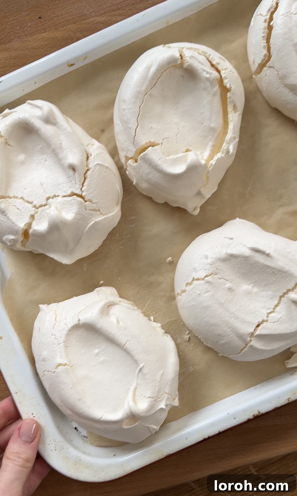 Baked lemon meringues cooling on a baking tray after coming out of the oven, showing crisp exteriors.