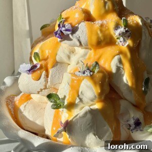 A festive tower of lemon meringues, adorned with lemon curd, fresh berries, and edible flowers for a special occasion.
