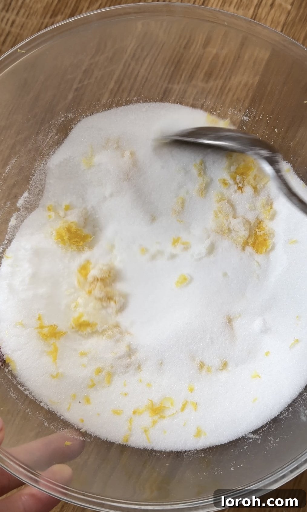 Mixing lemon zest and caster sugar together in a bowl, rubbing to release oils.