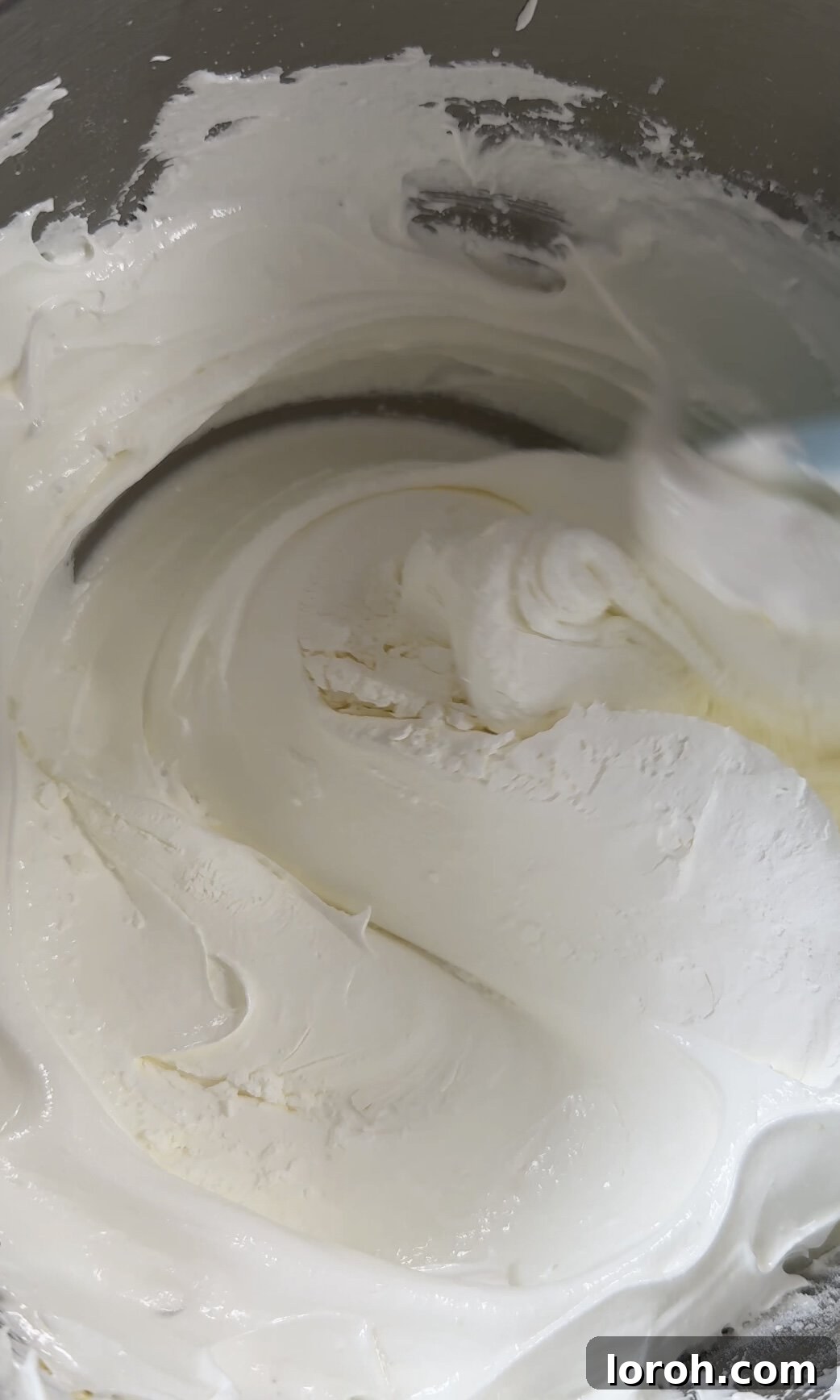 Gently folding cornflour and lemon juice into the meringue mixture with a spatula.