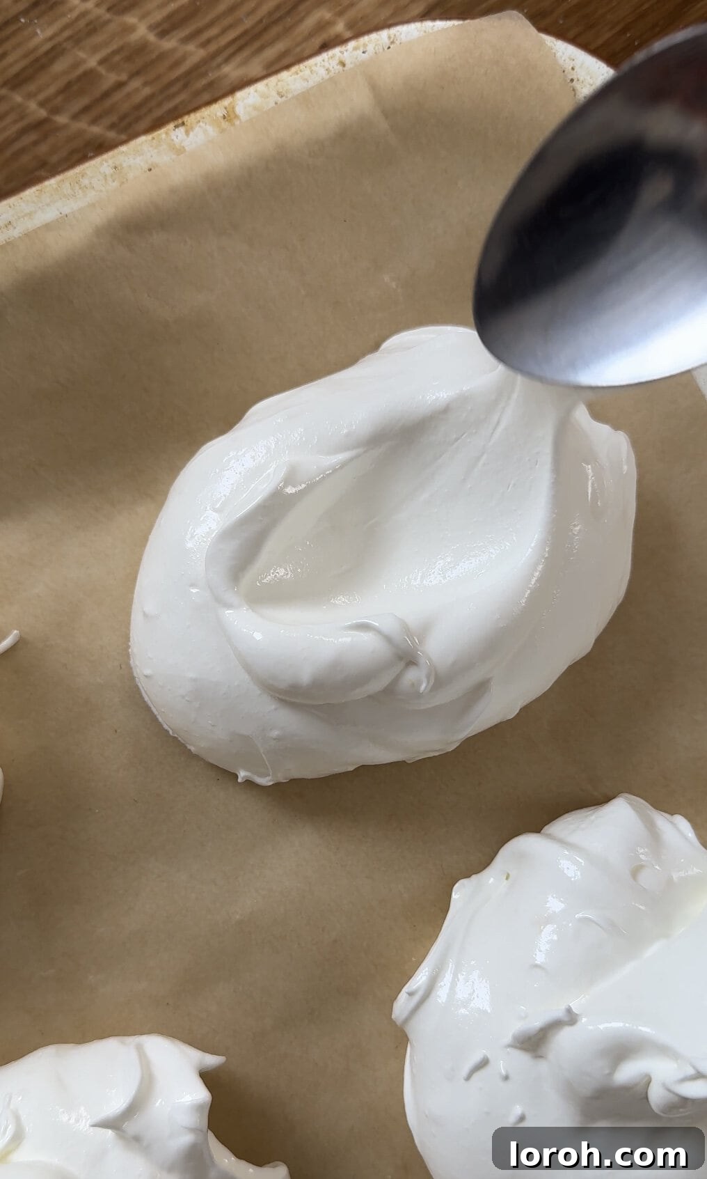 Creating small indentations in the center of the meringues with the back of a spoon.