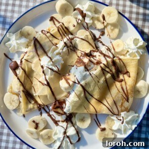 banana crepes on a plate with whipped cream and melted nutella.