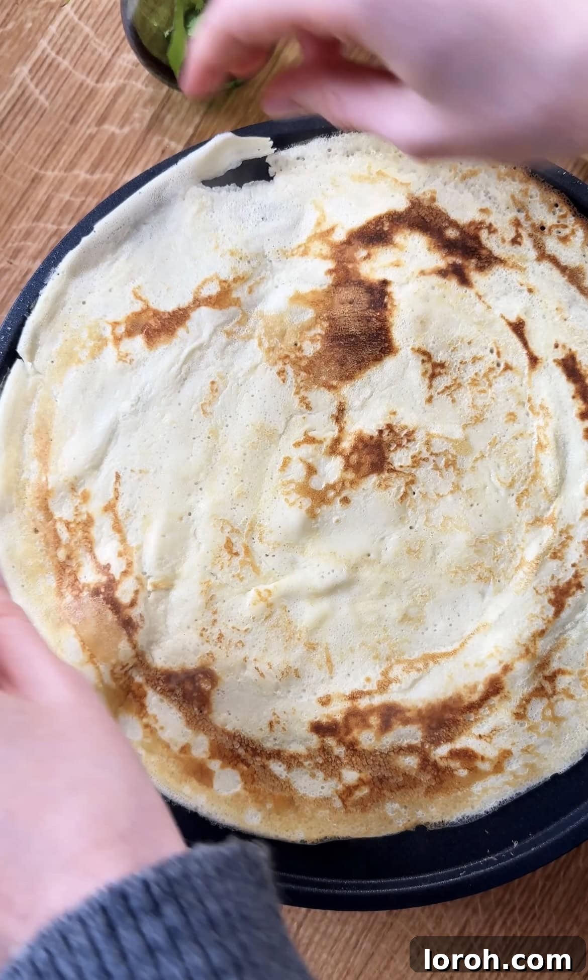 Golden Banana Crêpes 9 A banana crepe sizzling in a pan, cooking to a perfect golden brown.