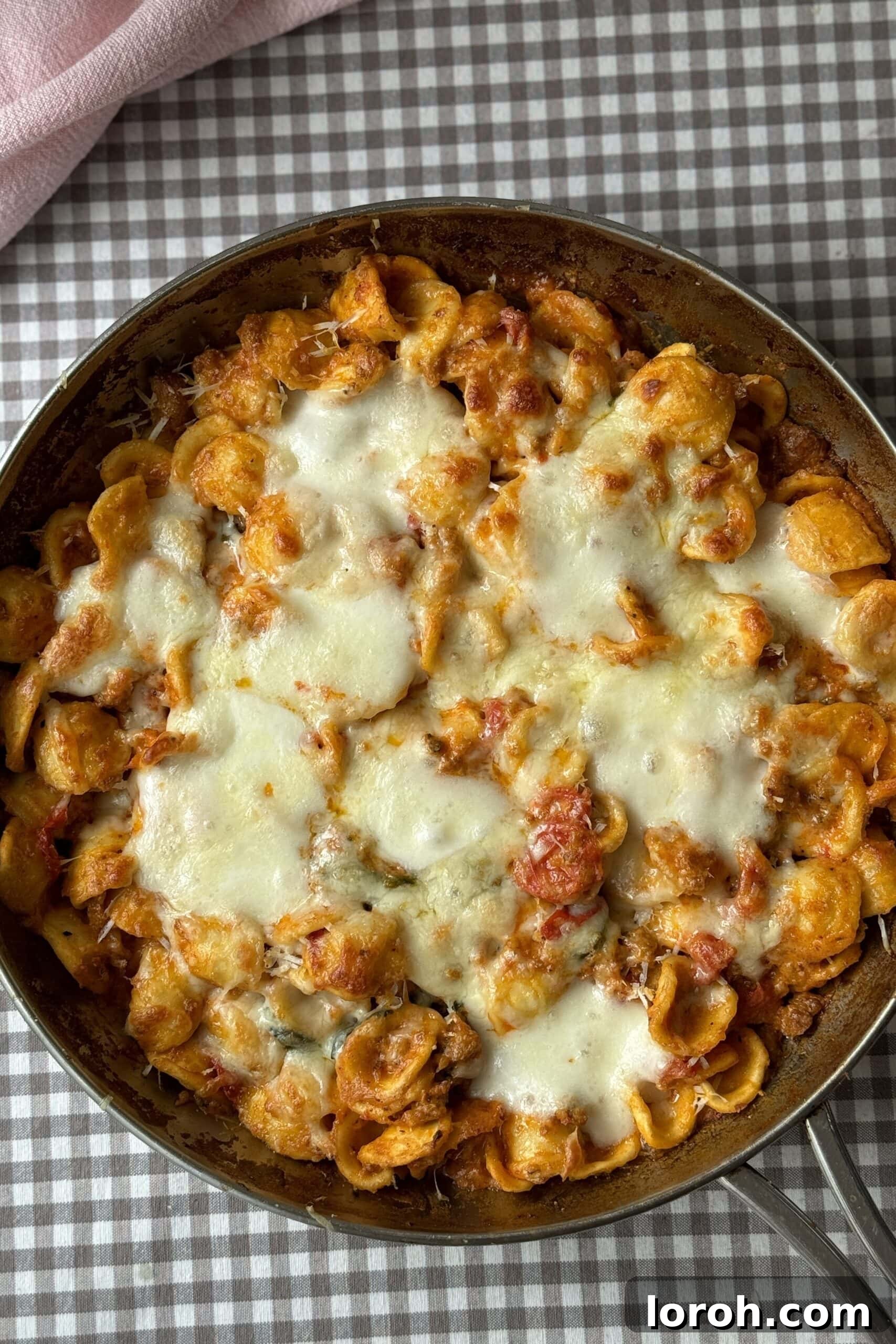 sausage pasta bake in silver pan with melted mozzarella.