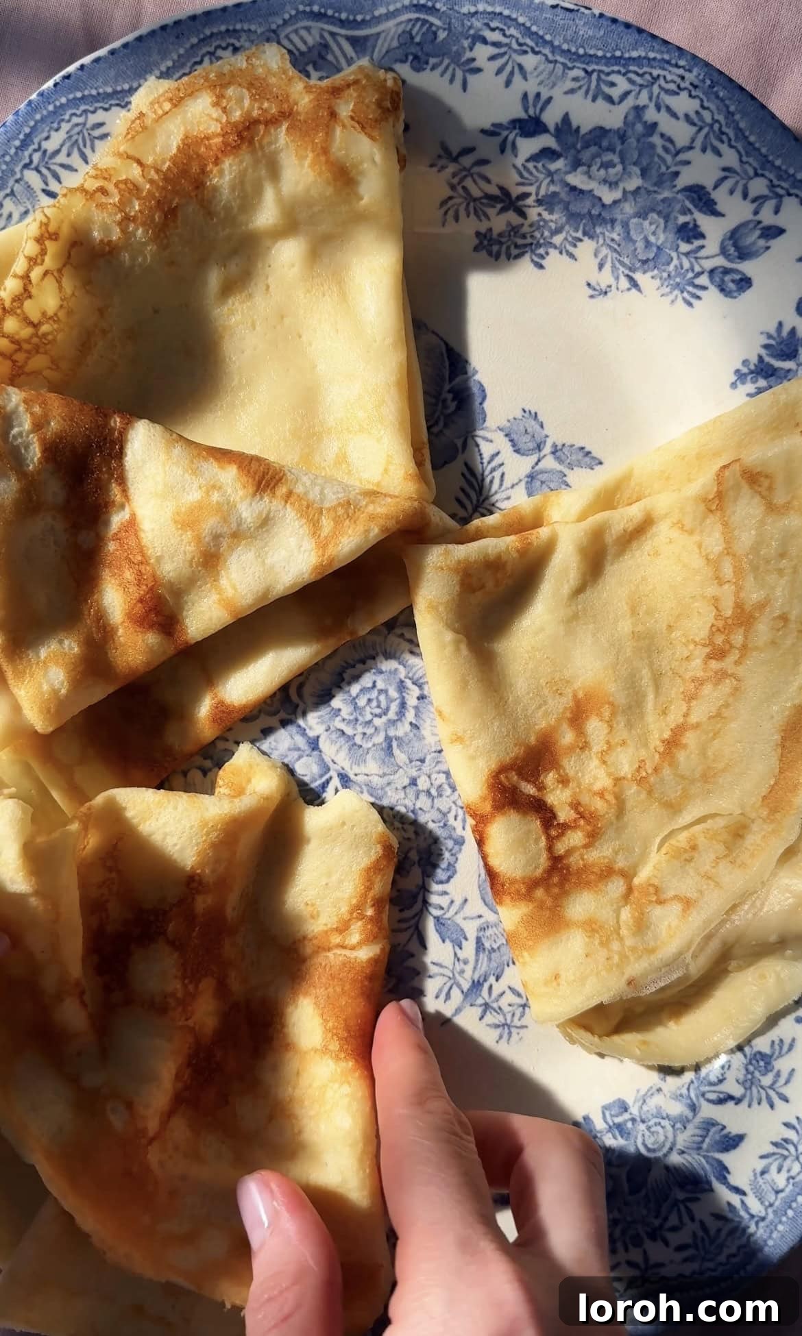 Stack of folded Pannekaker on a blue plate, ready to be served.