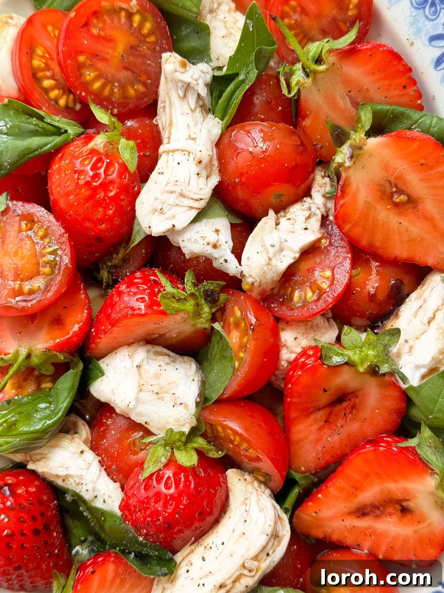 Close up of a vibrant strawberry and tomato salad, highlighting fresh, seasonal produce.