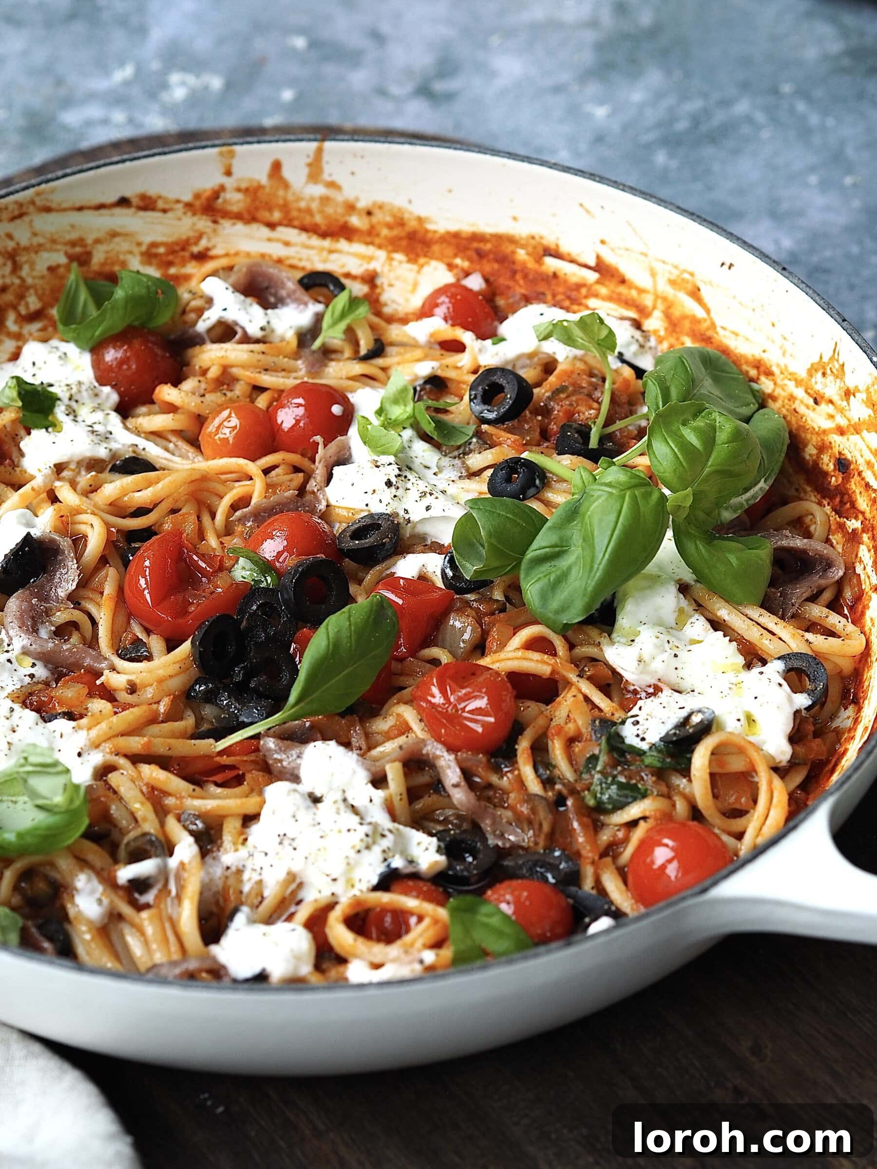 Cucina Povera in the style of Puttanesca, served in a shallow casserole dish topped with torn burrata and fresh basil.