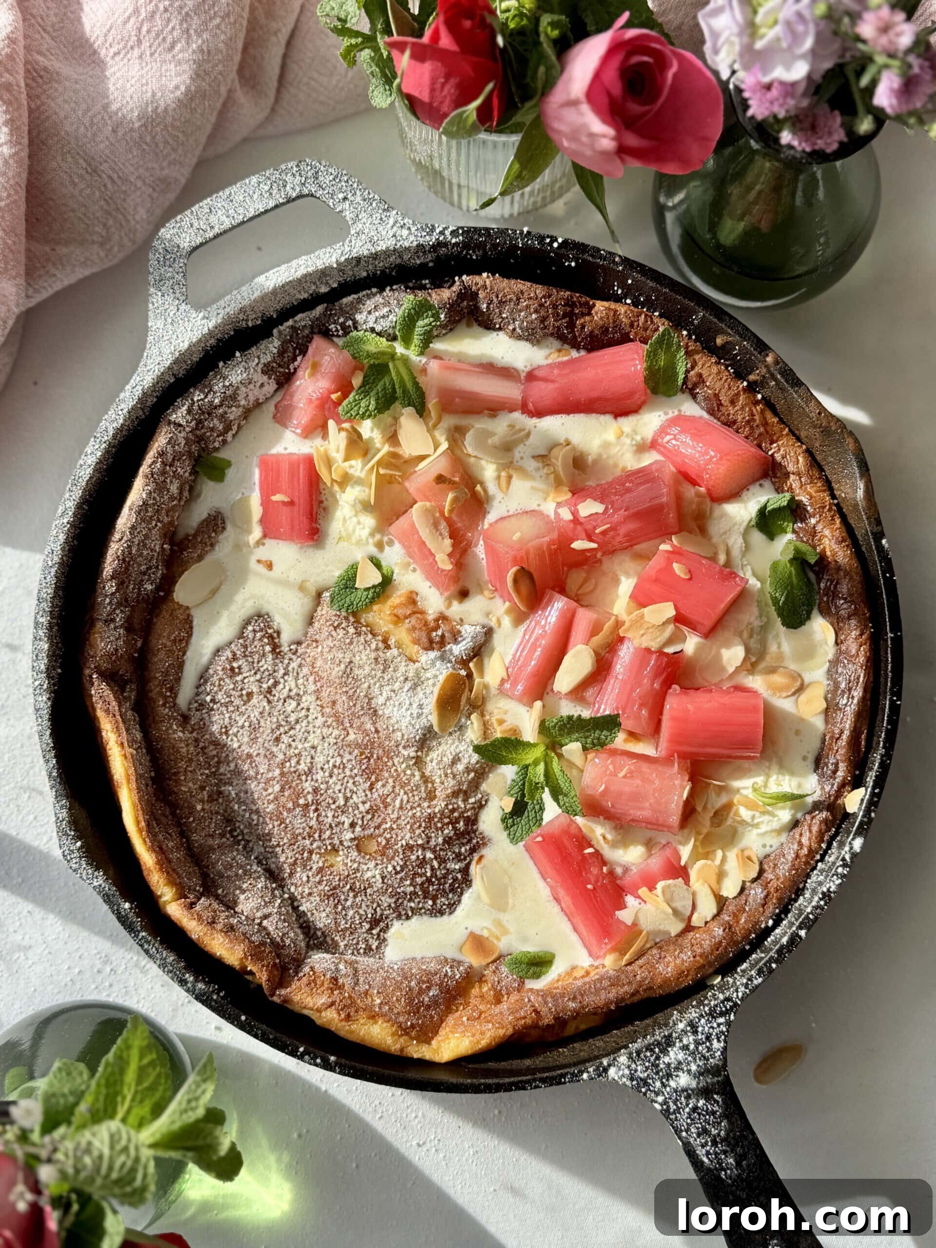 Pannukakku: Finland's Golden Oven-Baked Delight 2 pannukakku in a cast iron pan with whipped mascarpone cream and poached rhubarb.