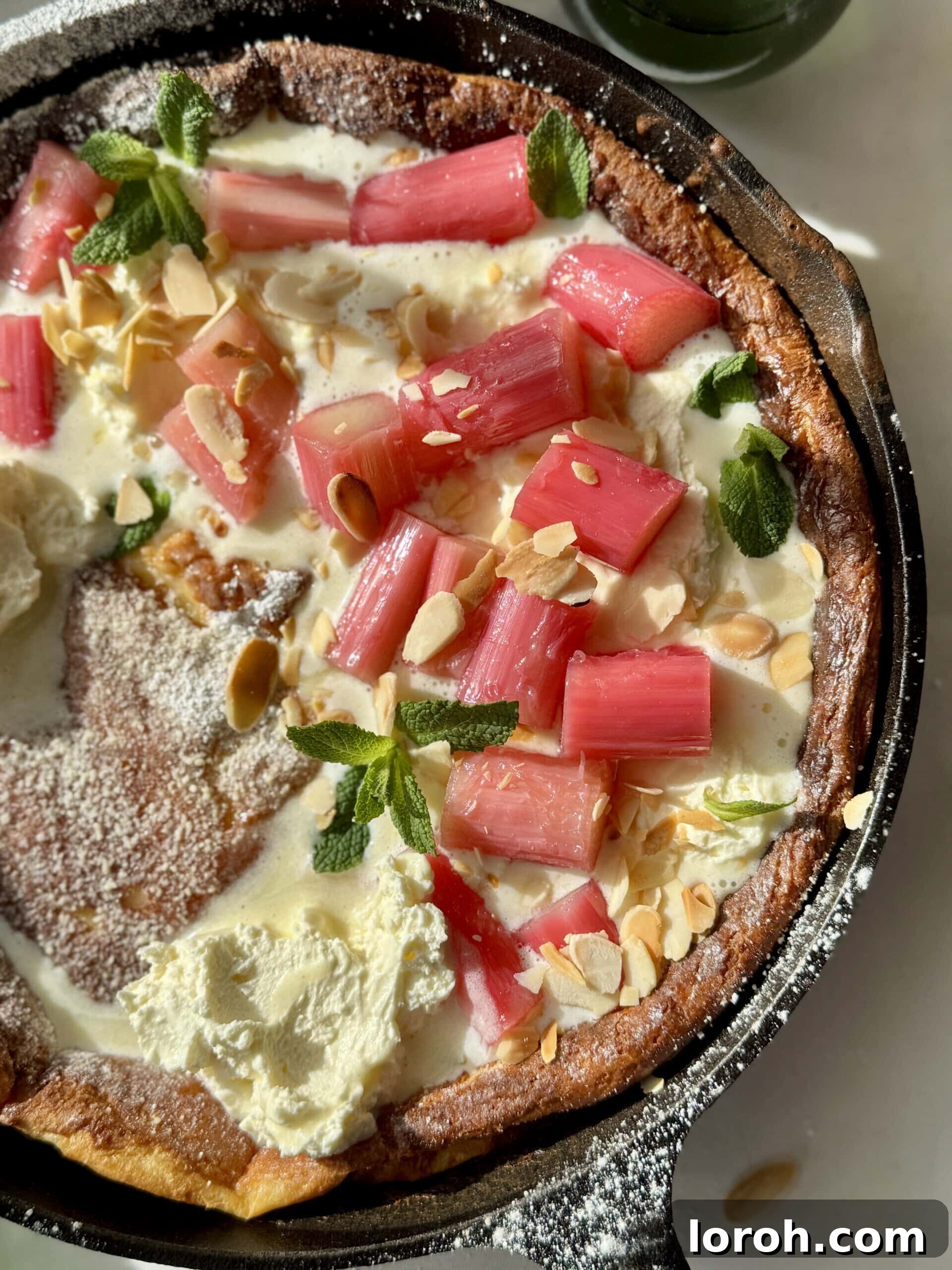 Pannukakku: Finland's Golden Oven-Baked Delight 3 pannukakku in a cast iron pan with whipped mascarpone cream and poached rhubarb.