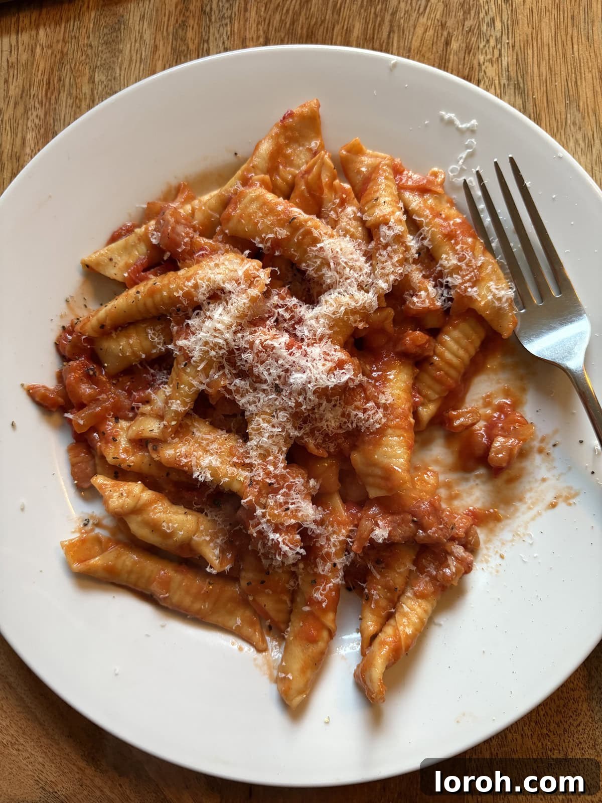 Garganelli pasta being tossed in Amatriciana sauce in a pan.