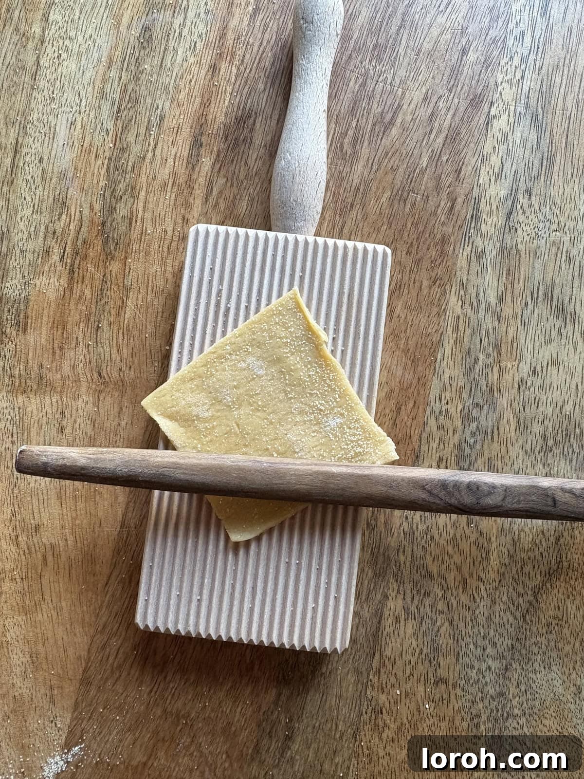 Placing pasta square onto a ridged board for shaping.