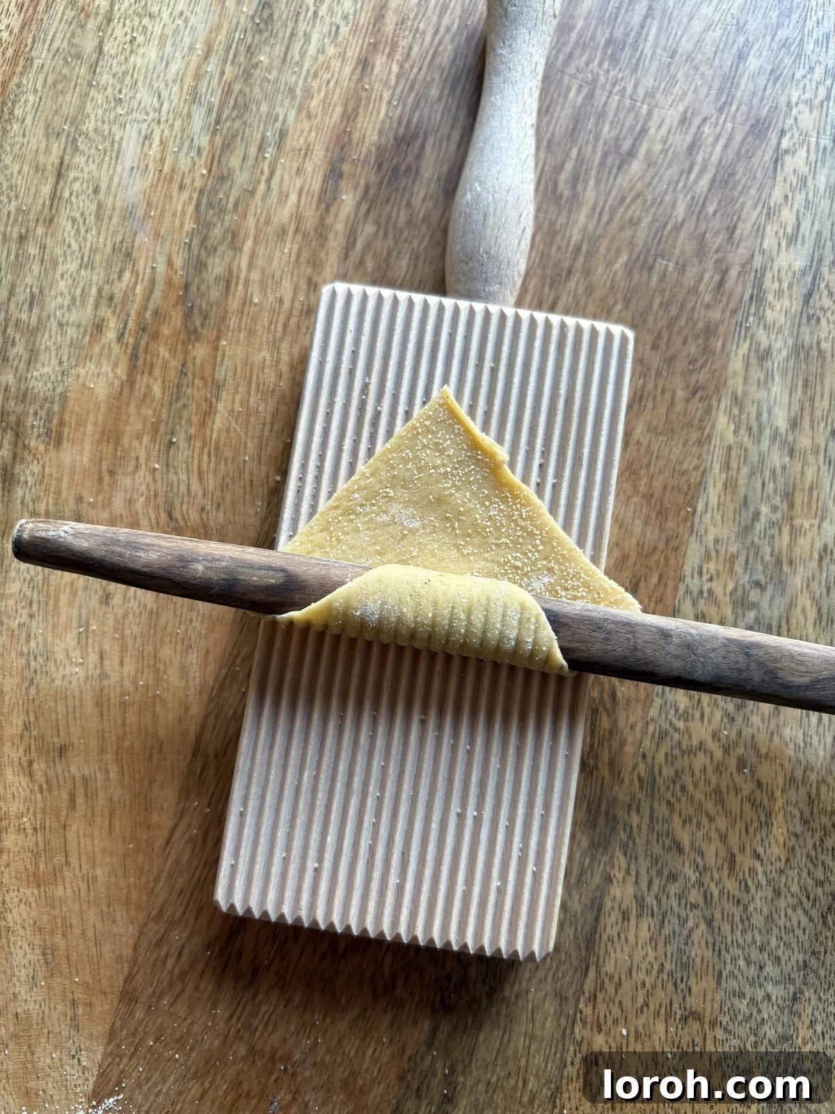 Beginning to roll garganelli pasta with a wooden stick.