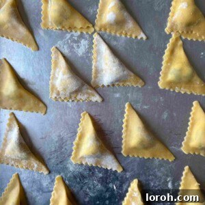 Folded triangoli on a silver tray, ready for cooking.