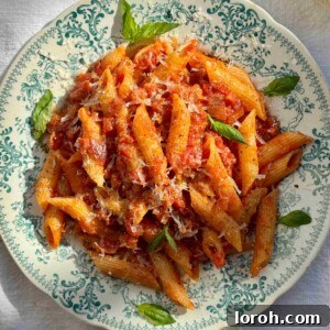 A beautiful blue bowl filled with Penne Amatriciana, garnished and ready to be served.