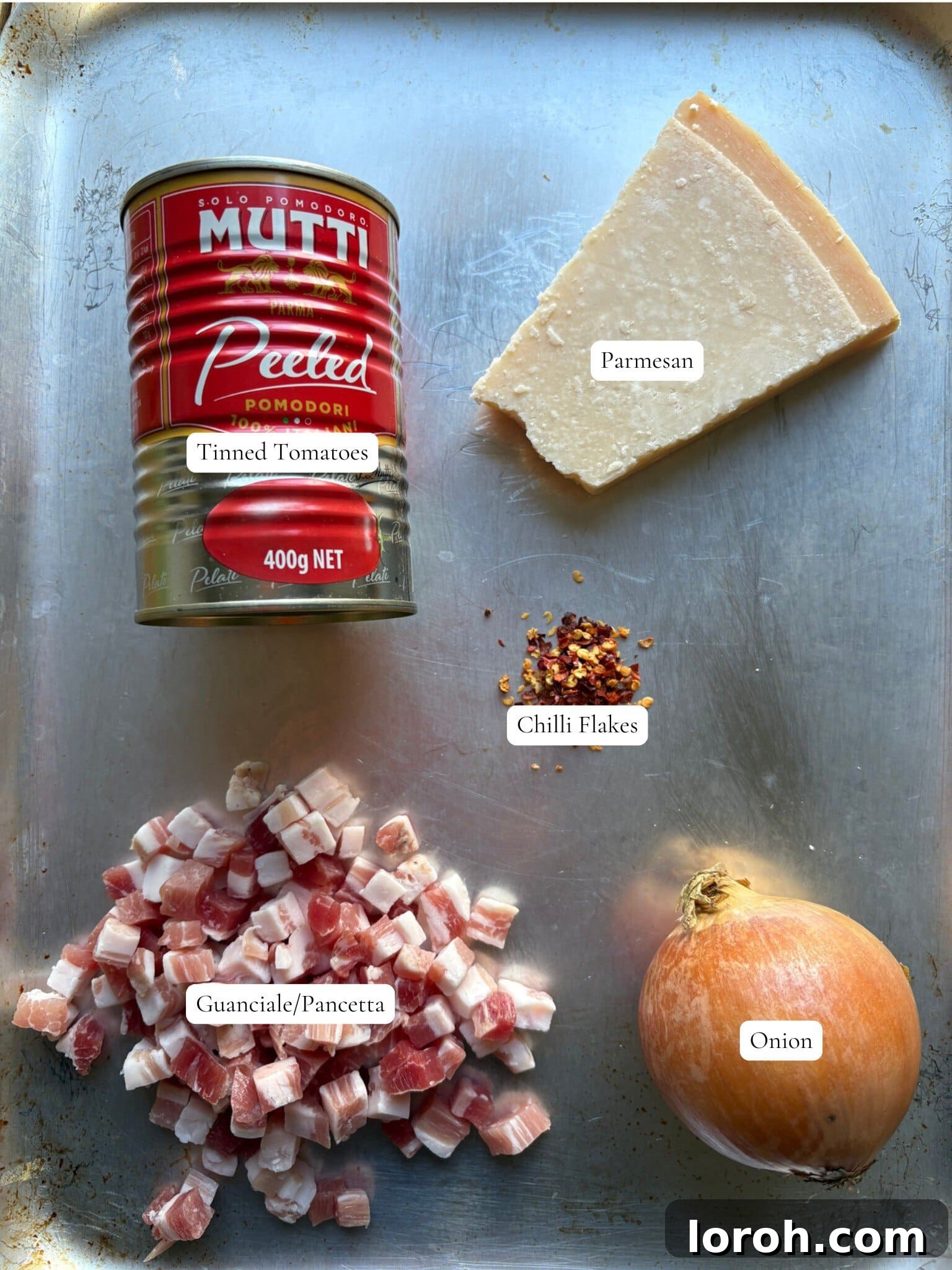 Guanciale Tomato Penne 3 Carefully arranged ingredients for Amatriciana sauce, including guanciale, tinned tomatoes, onion, chili flakes, and Parmesan cheese.