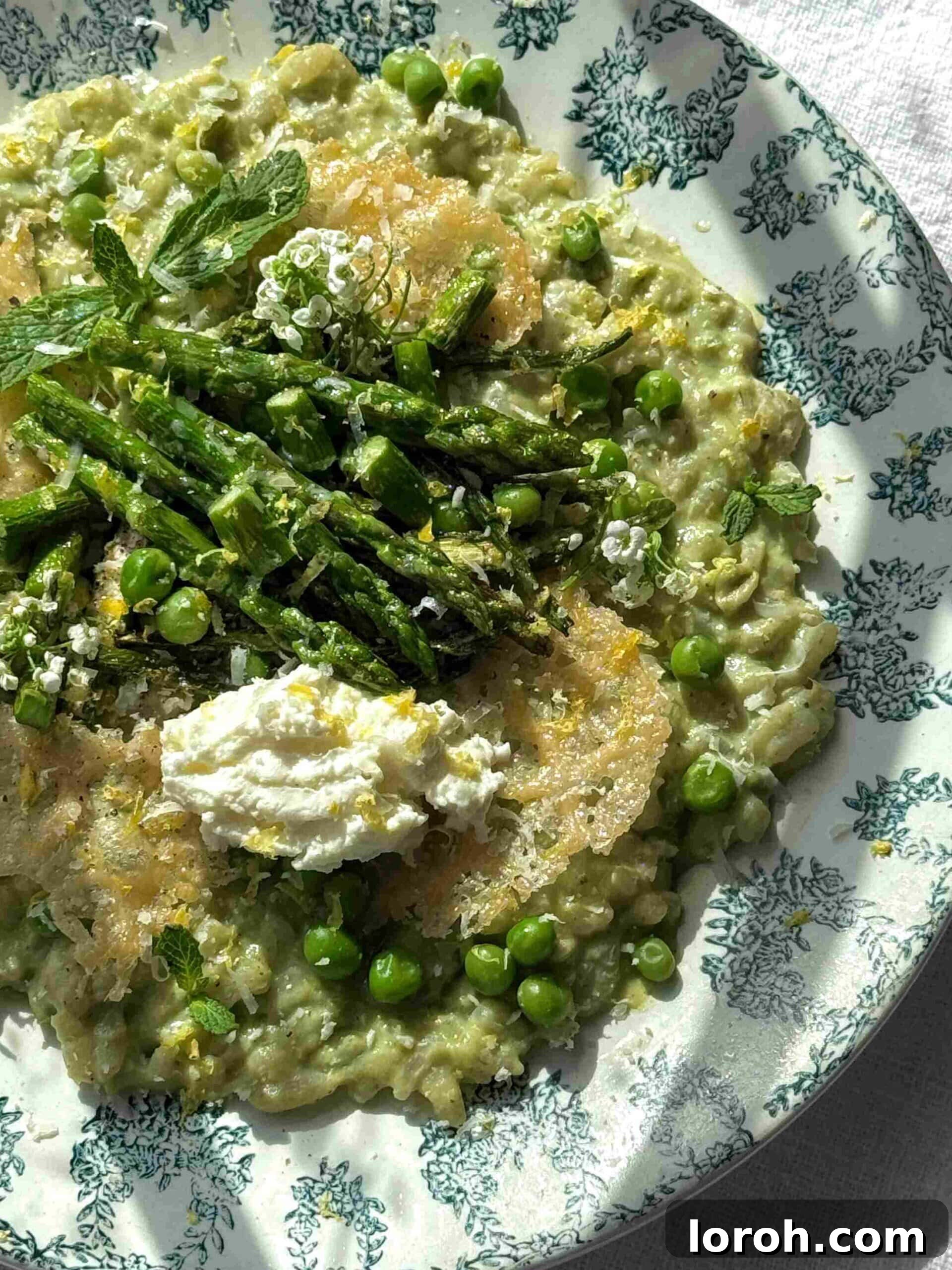 Vibrant Spring Asparagus Risotto 3 A close-up shot of creamy Asparagus Risotto, highlighting the texture of the rice and pieces of asparagus on a blue plate.