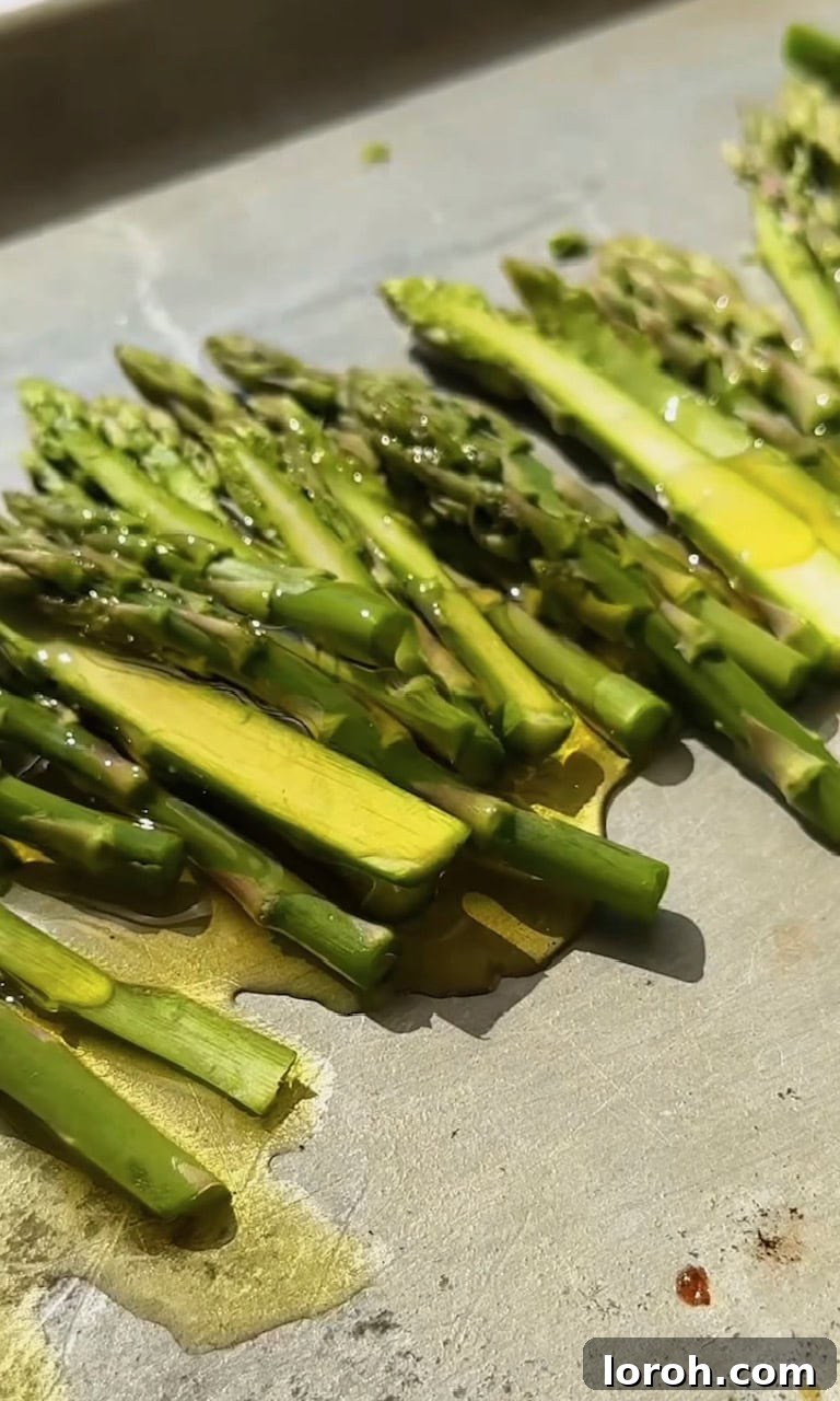 Vibrant Spring Asparagus Risotto 5 Asparagus spears arranged on a baking tray, lightly drizzled with olive oil, salt, and pepper, ready for roasting.