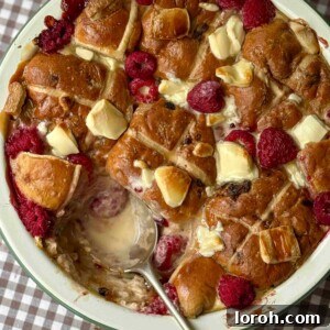 Hot Cross Bun Bread and Butter Pudding ready to be served, with a spoon taking a scoop.