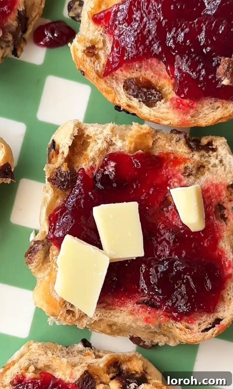 Image showing chopped white chocolate being sprinkled onto a jam-spread hot cross bun.